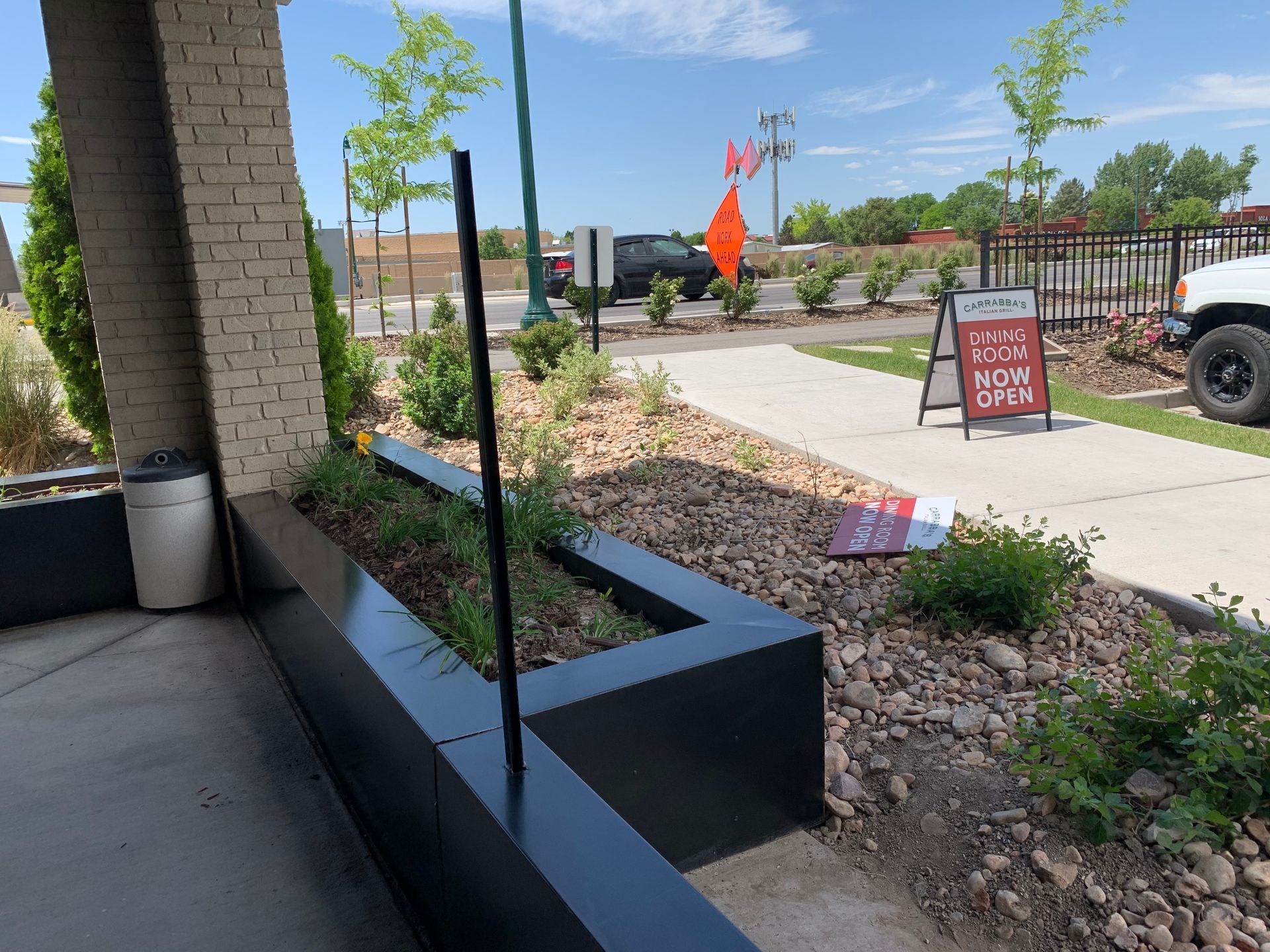 Exterior view of building with a flower bed, sign, and street in the background.