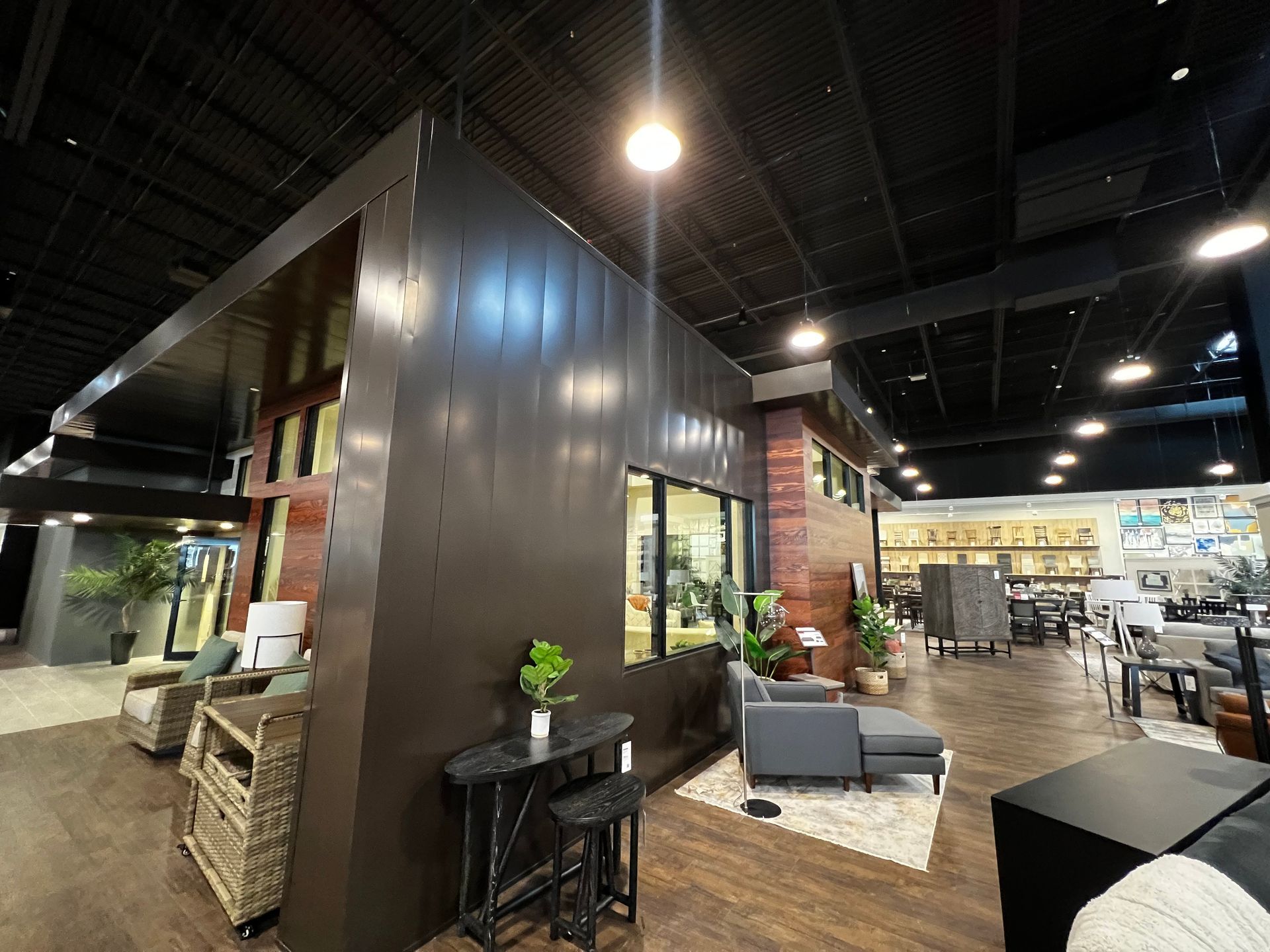 Furniture showroom interior with dark metallic wall and display areas.