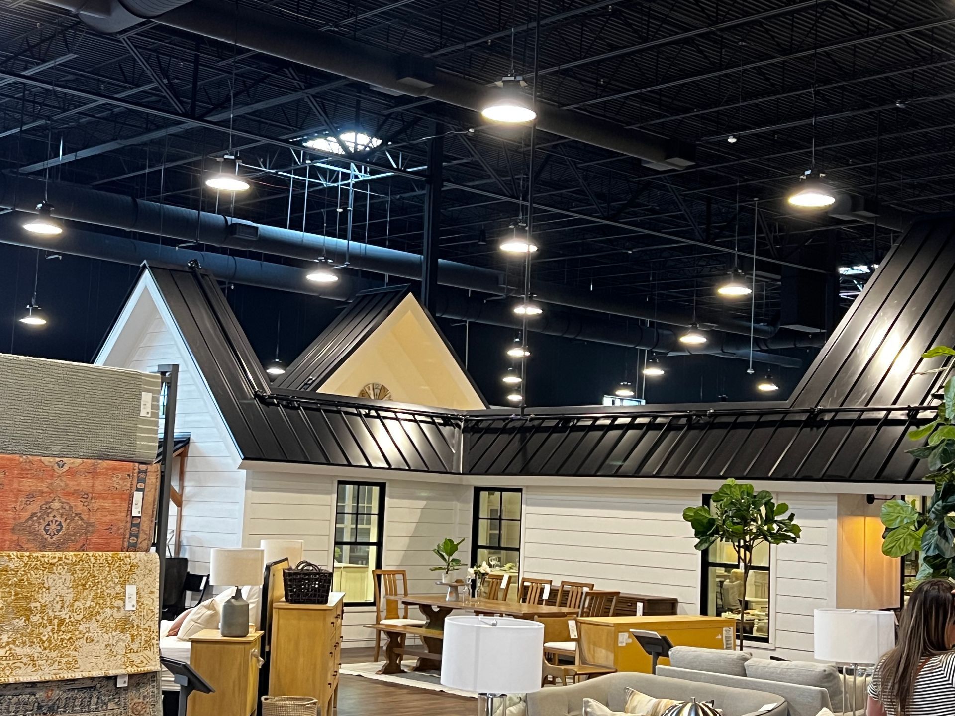 Interior of a furniture store with overhead lights and a house-shaped display.