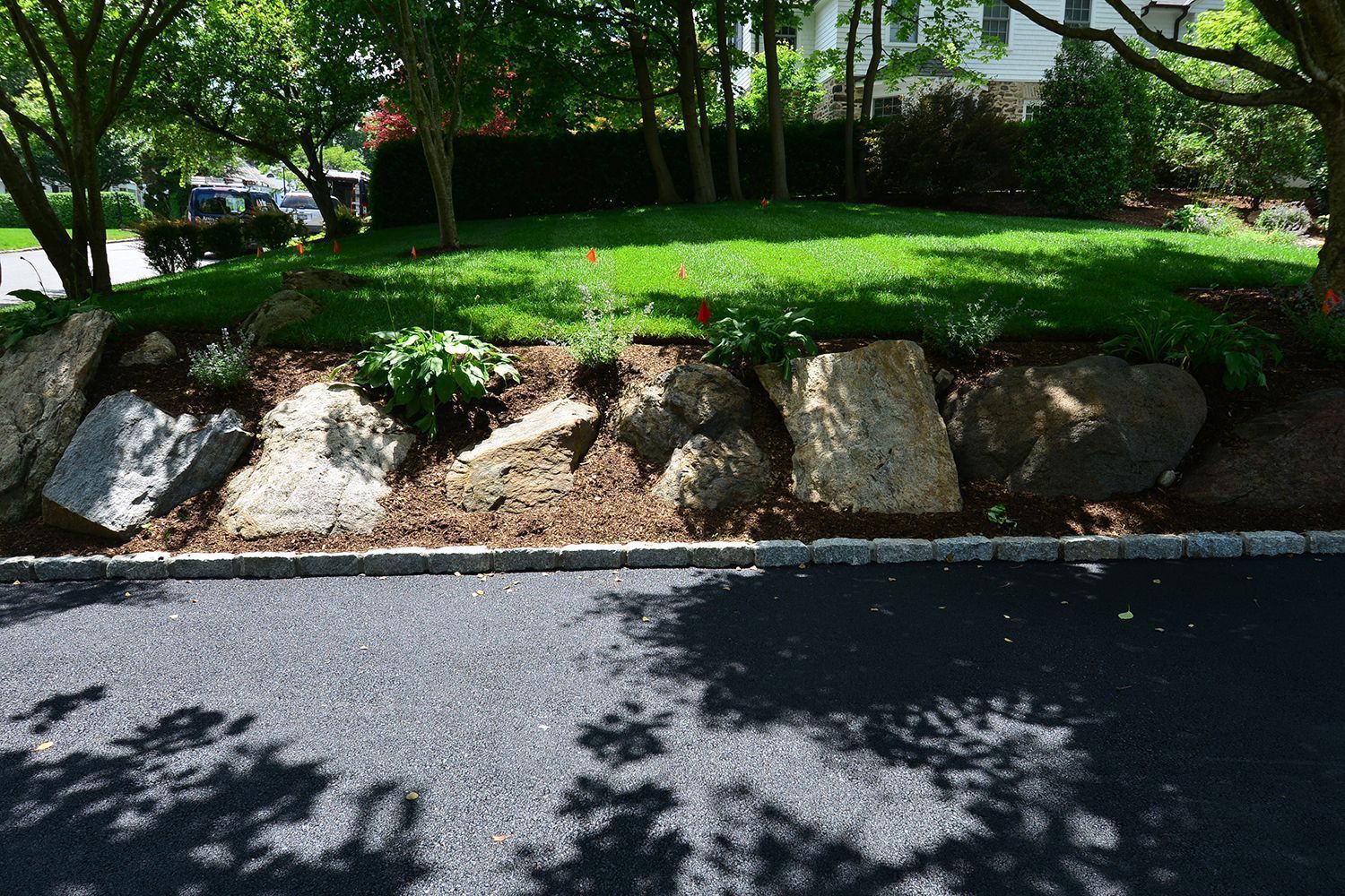 large rocks forming a retaining wall with green grass and mulch bed above
