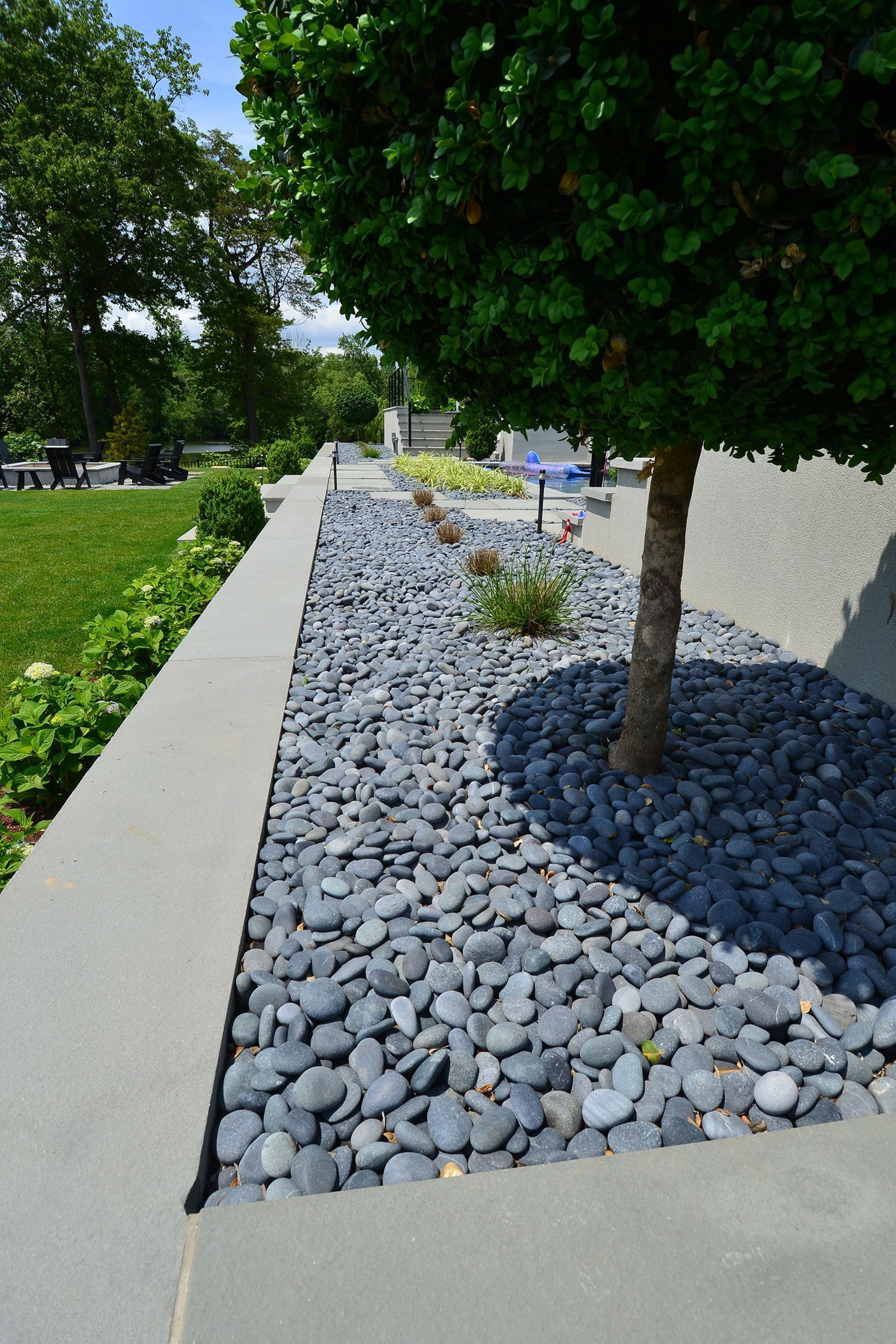 gray river rocks surround a tree in a modern outdoor landscape