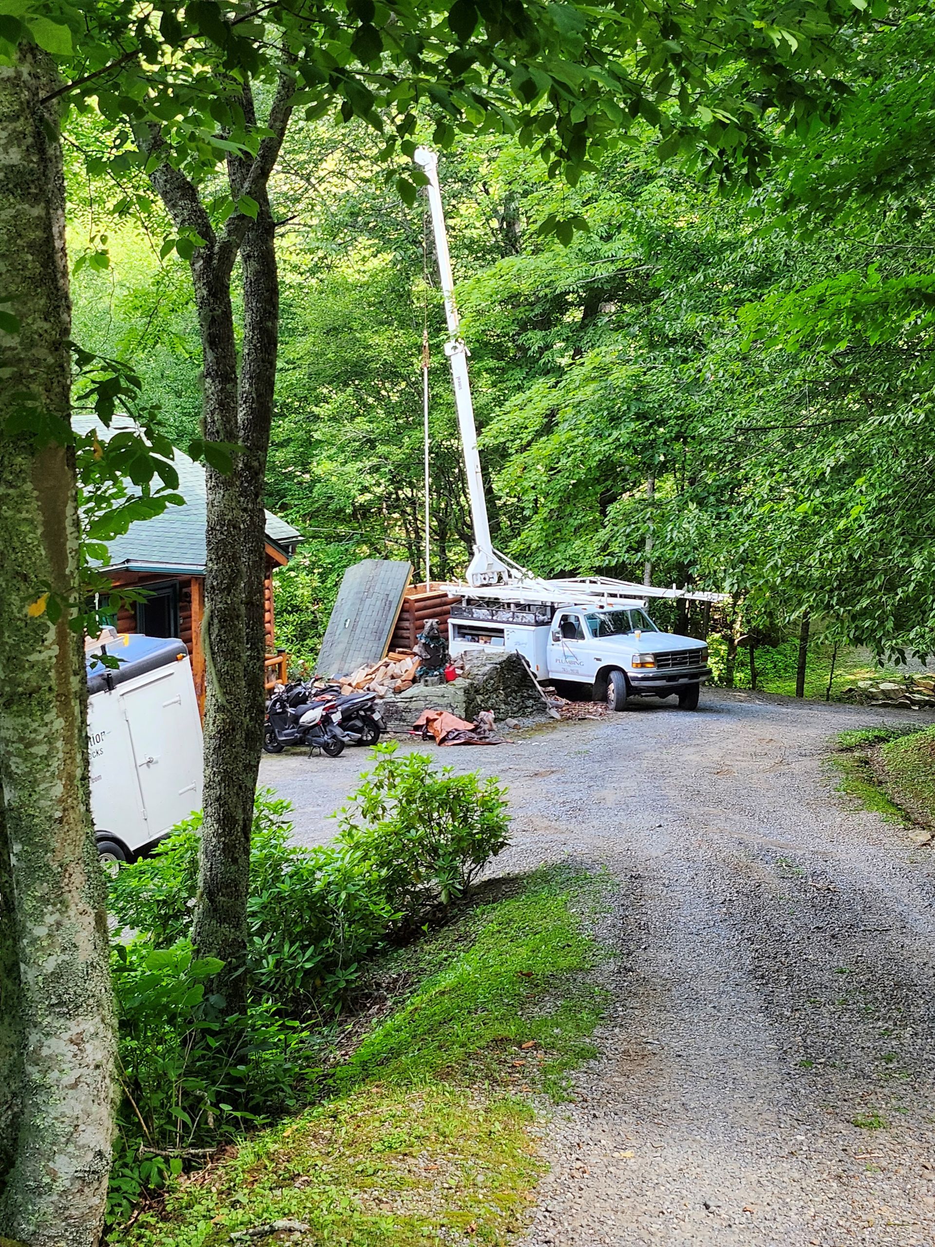 A white truck is parked on the side of a gravel road in the woods