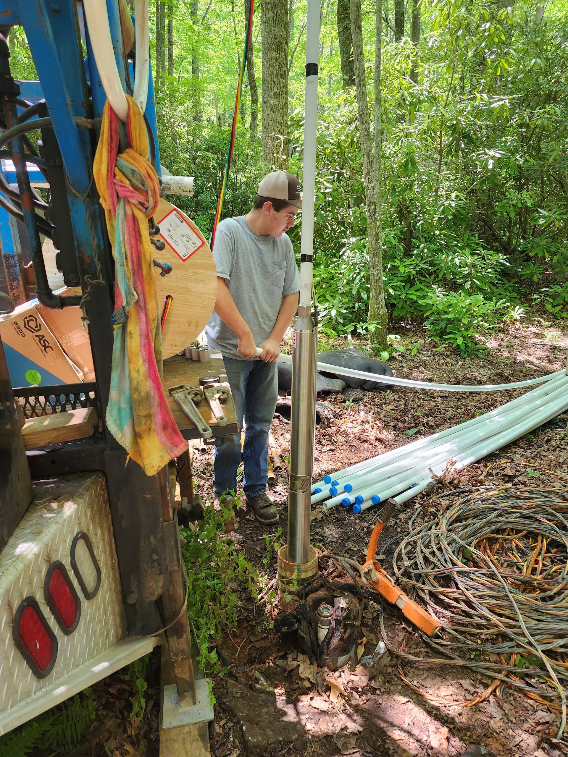 A man is standing next to a machine in the woods