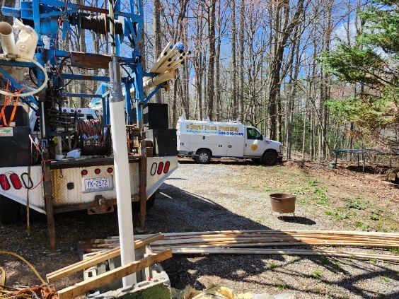 A blue and white truck is parked in a driveway next to a white van