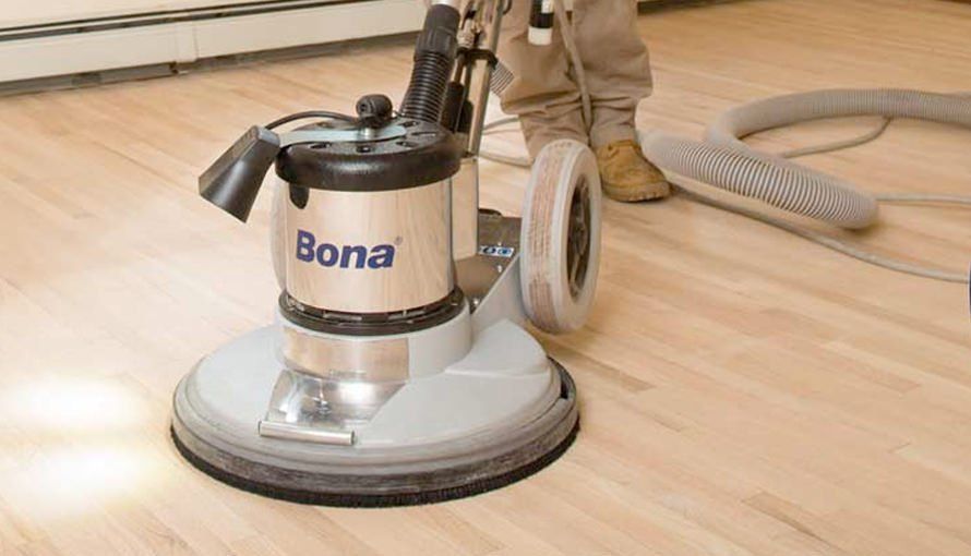 A person refinishing hardwood floors with a Bona floor sander.