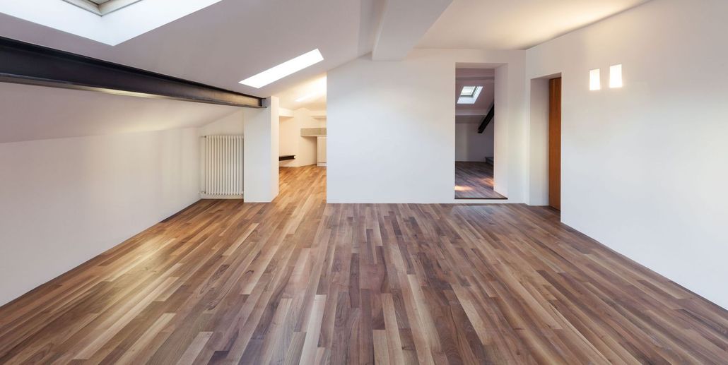 Empty room with hardwood floor, white walls, and skylights.