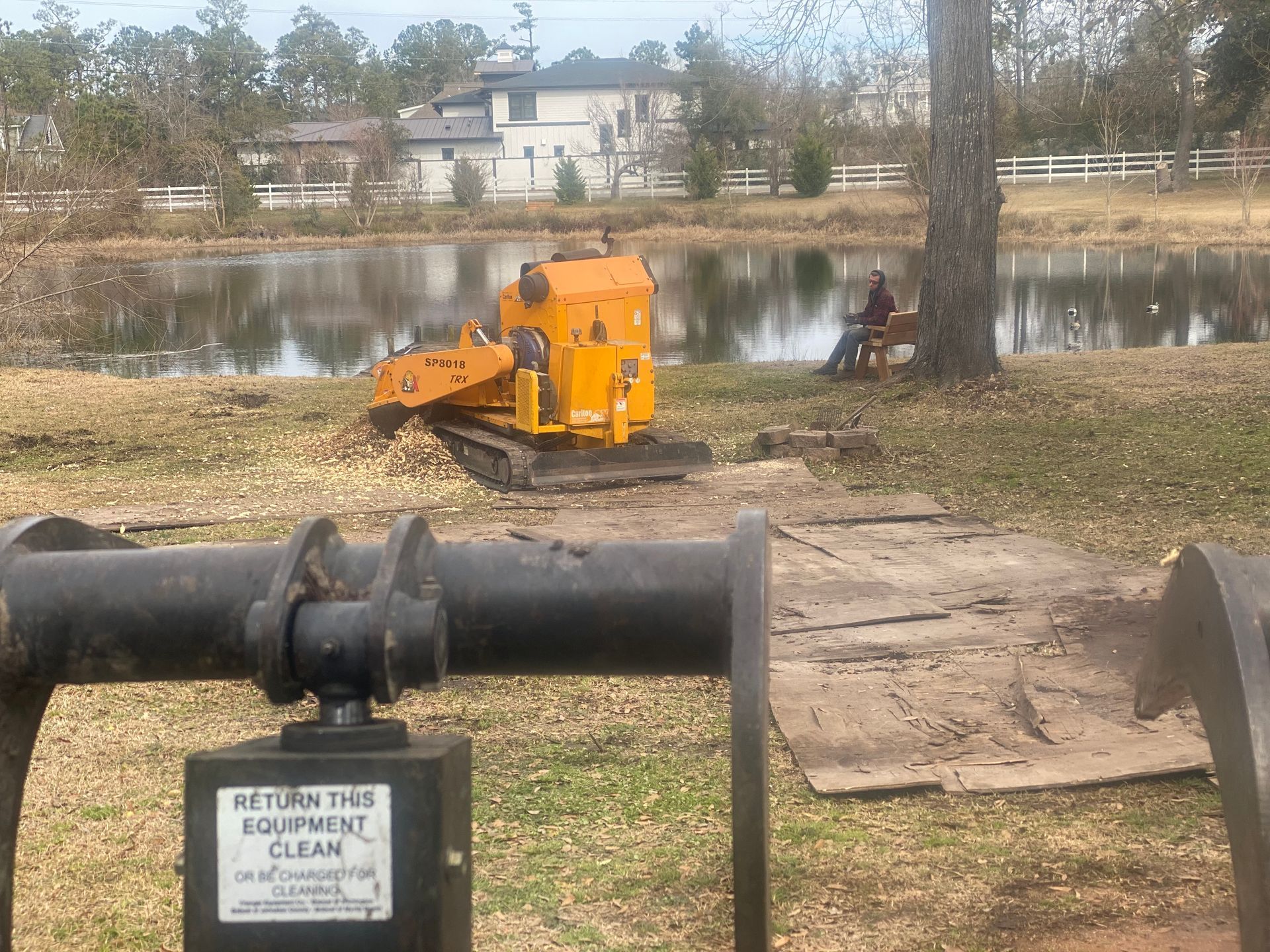 A yellow tractor is parked in front of a lake.