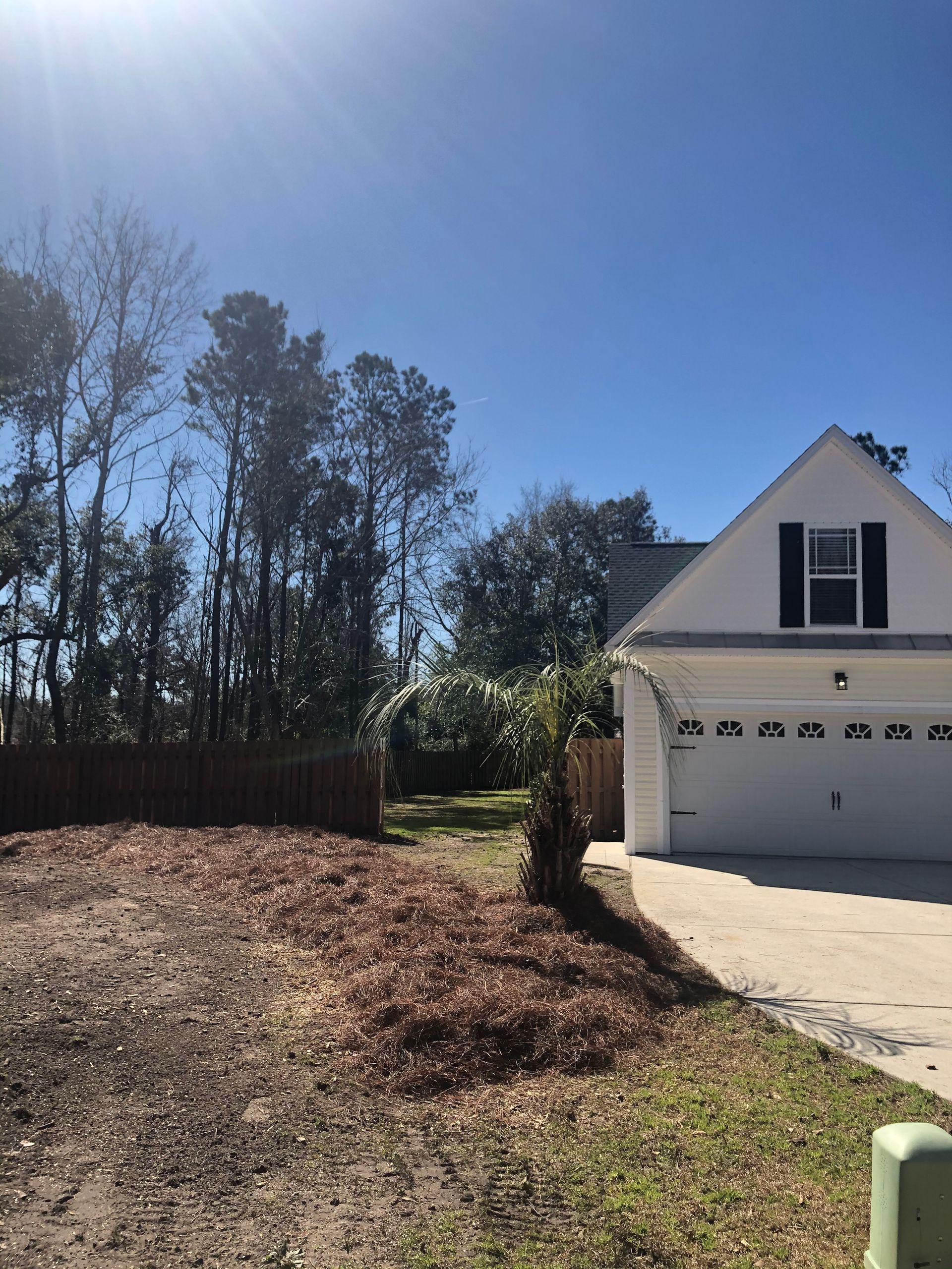 A white house with a garage and trees in the background