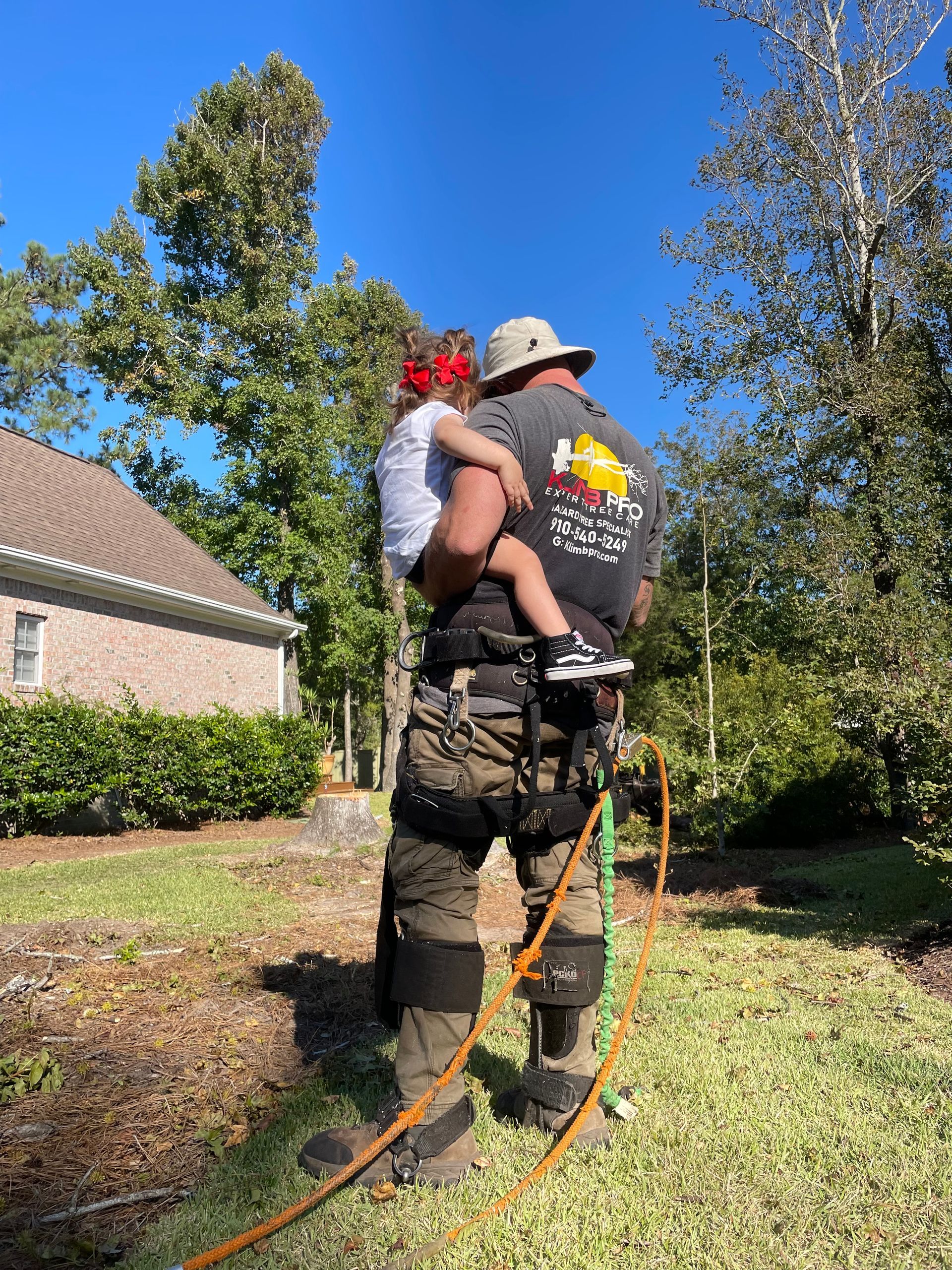 A man is holding a child in his arms while standing next to a tree.