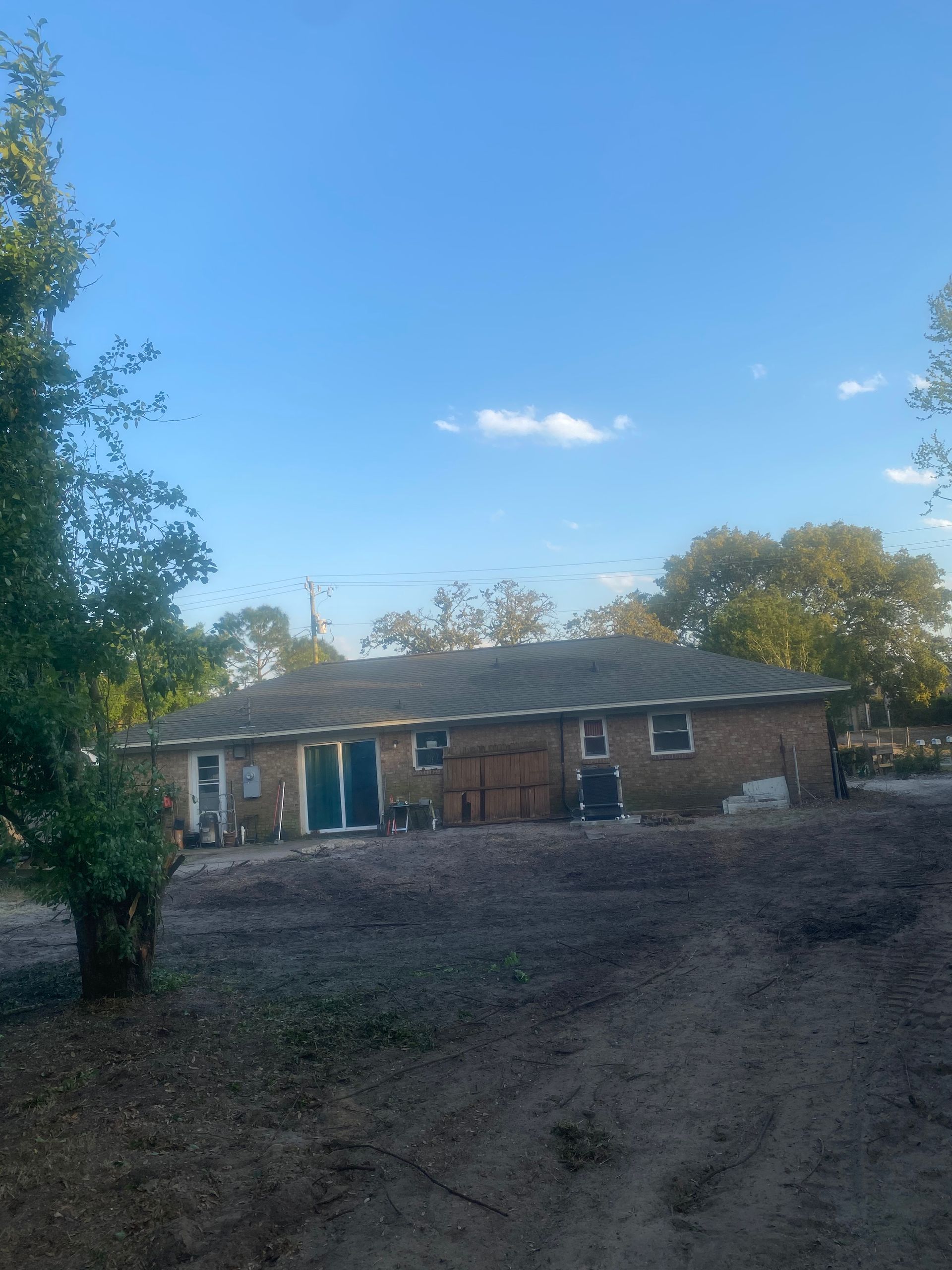 A brick house is sitting in the middle of a dirt field.