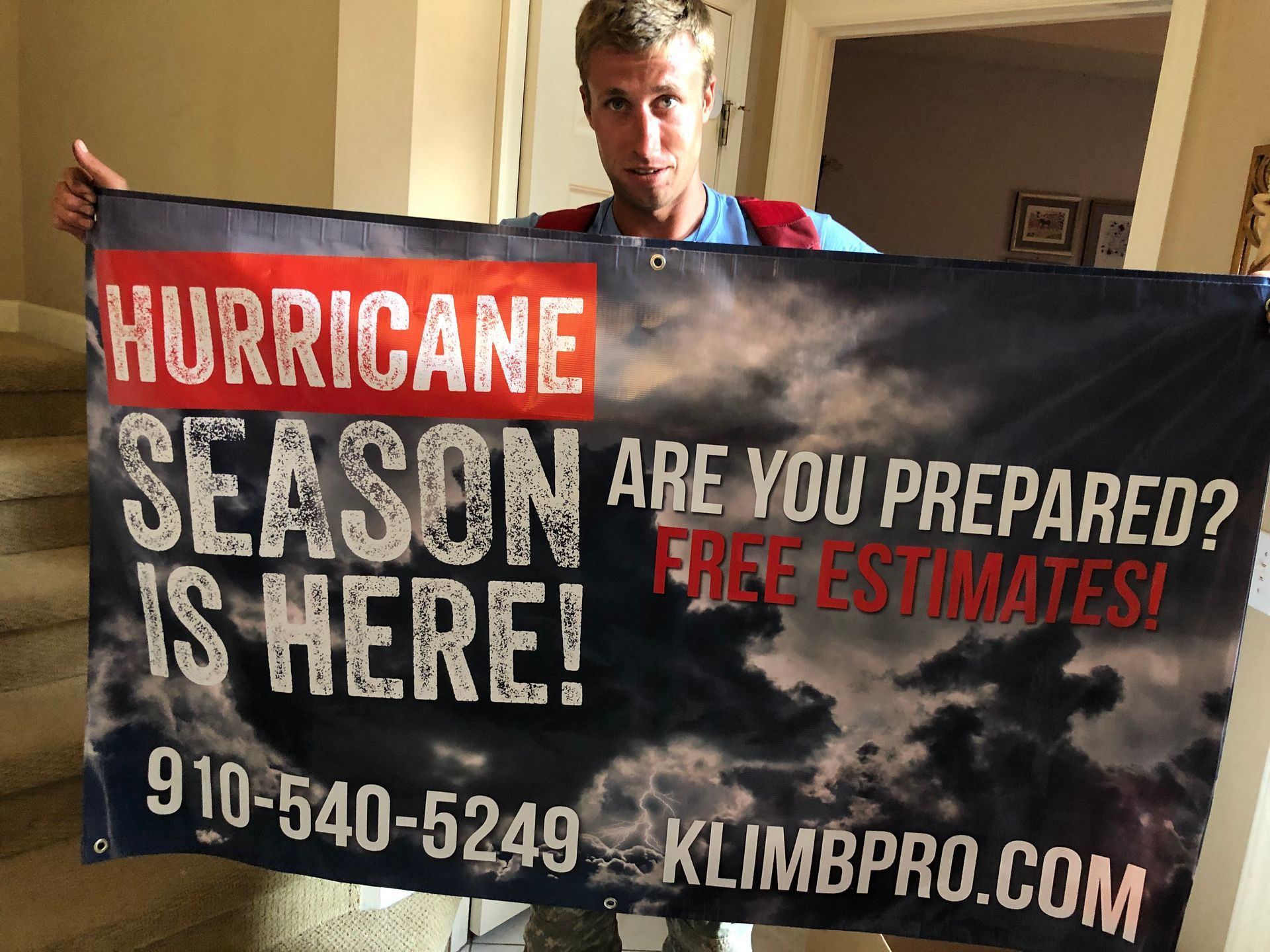 A man is holding a banner that says hurricane season is here