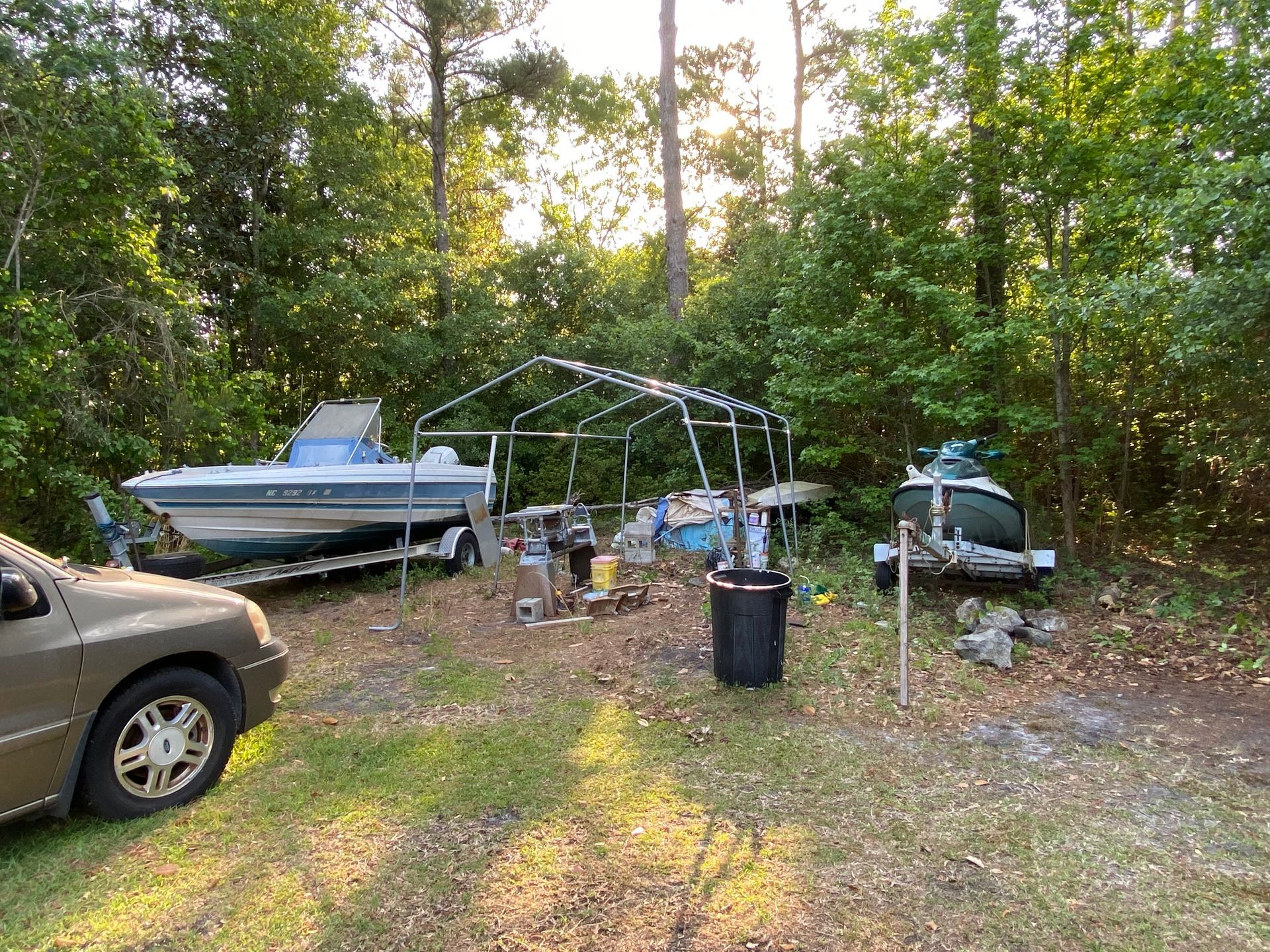 A car is parked in a grassy area next to a boat.
