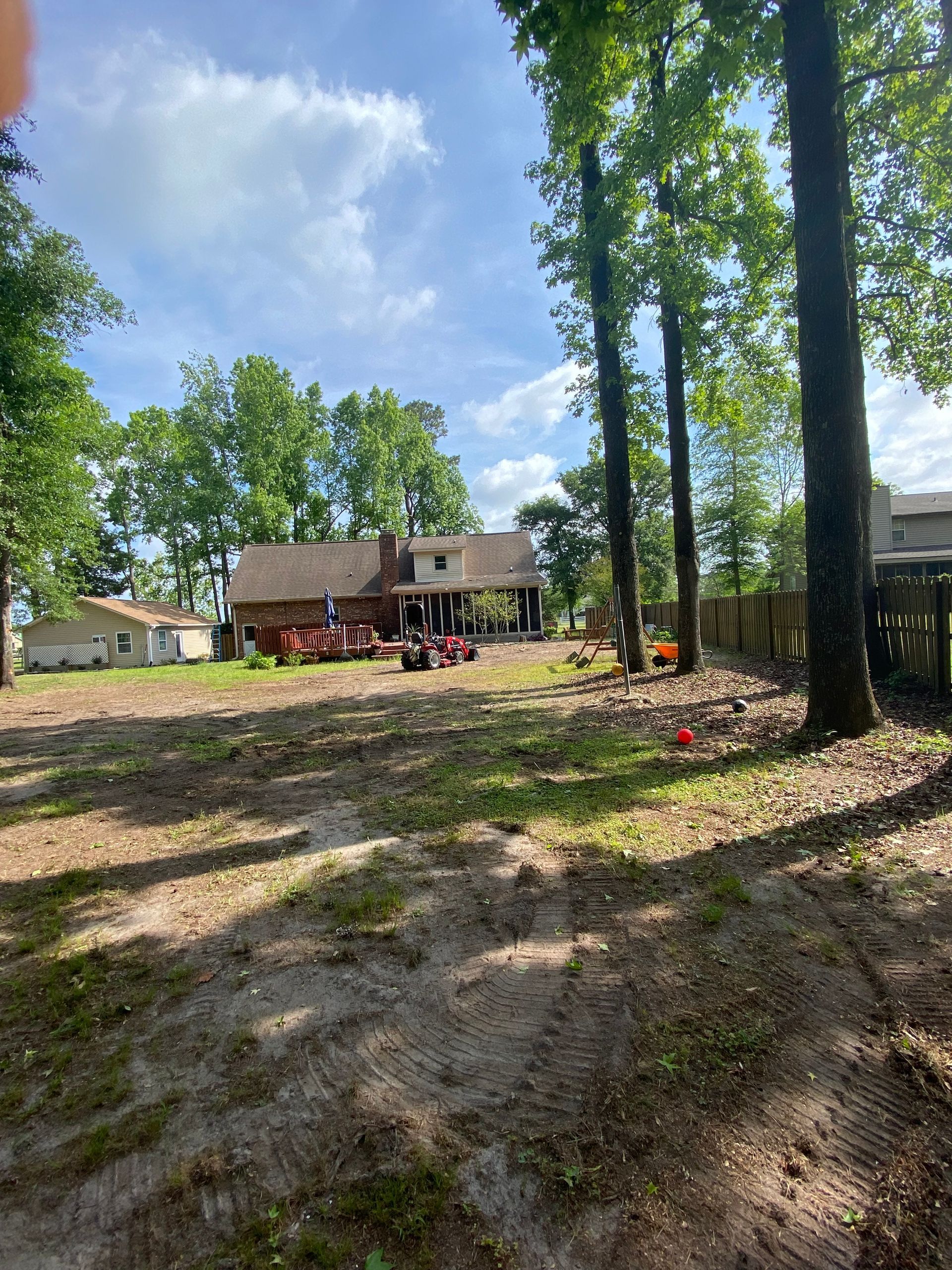 A house is sitting in the middle of a dirt field surrounded by trees.