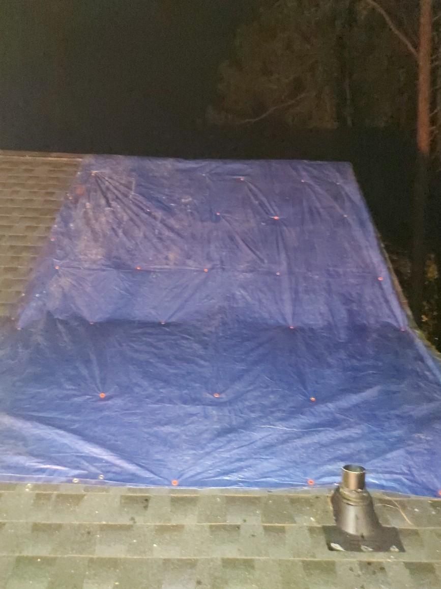 A large blue tarp is sitting on top of a roof.