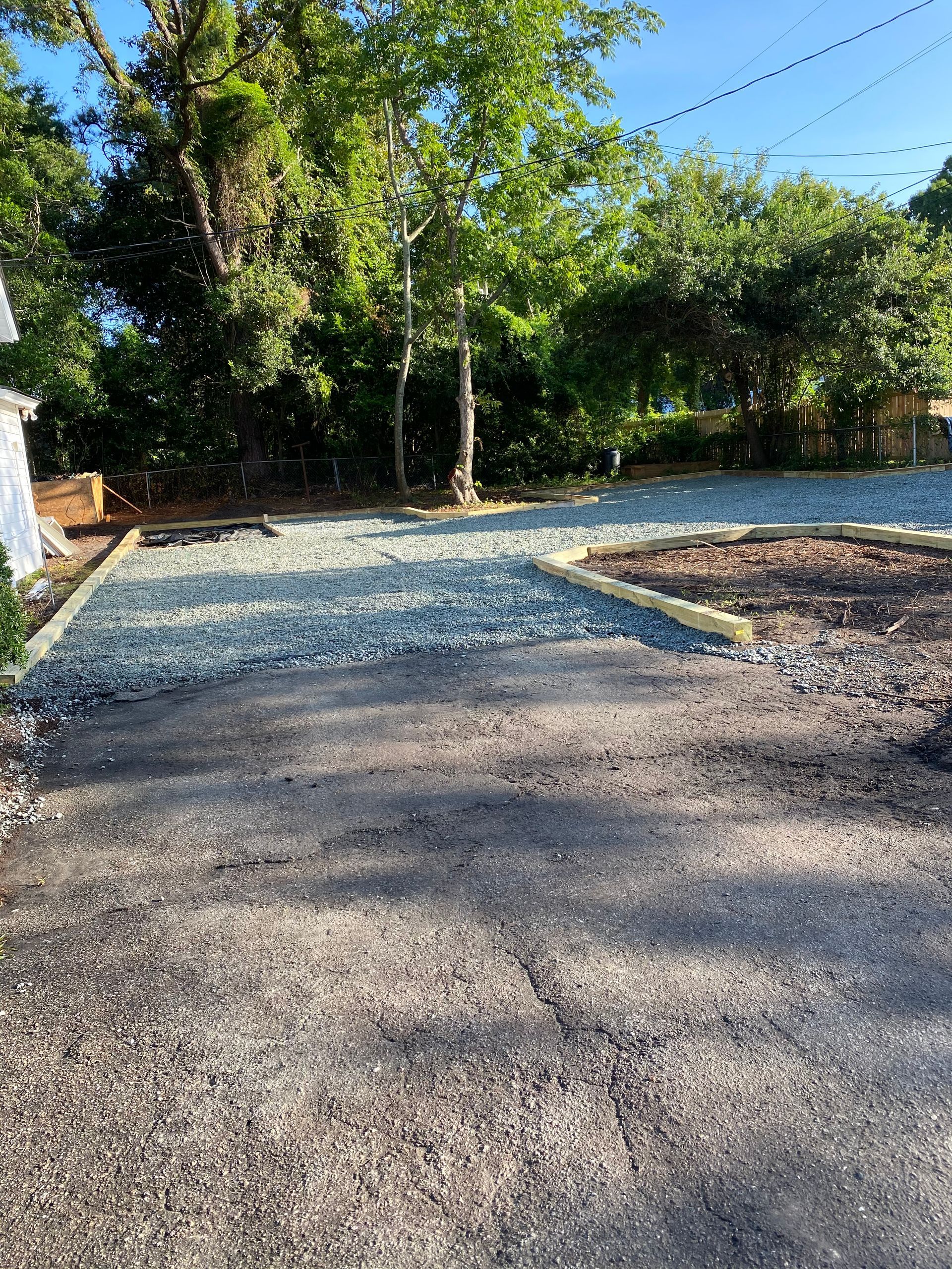 A gravel driveway leading to a house with trees in the background.