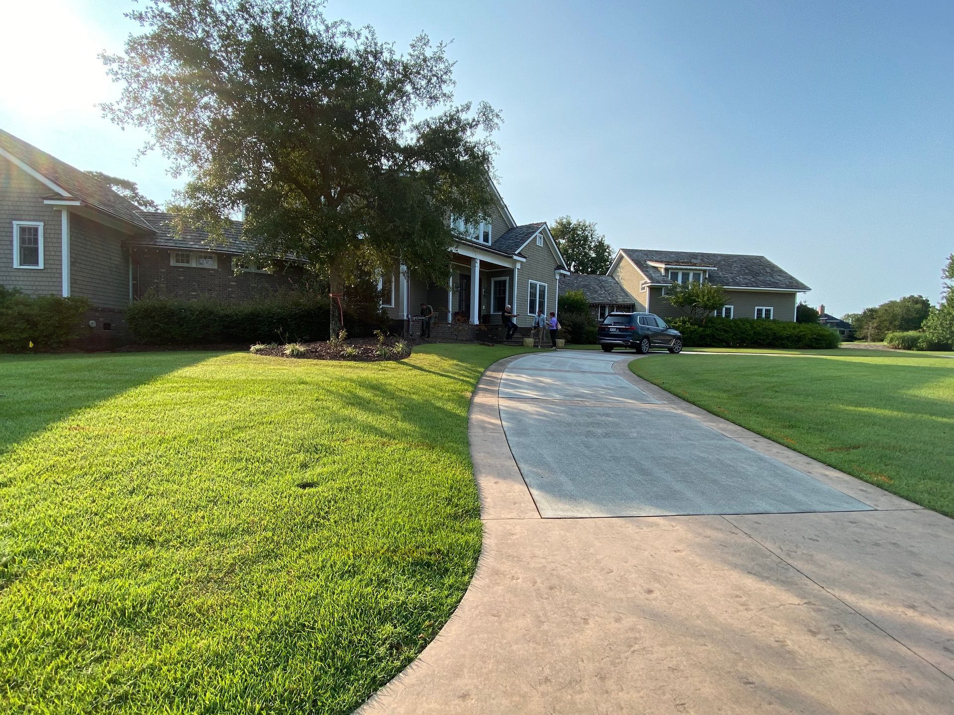 A driveway leading to a large house with a car parked in front of it.