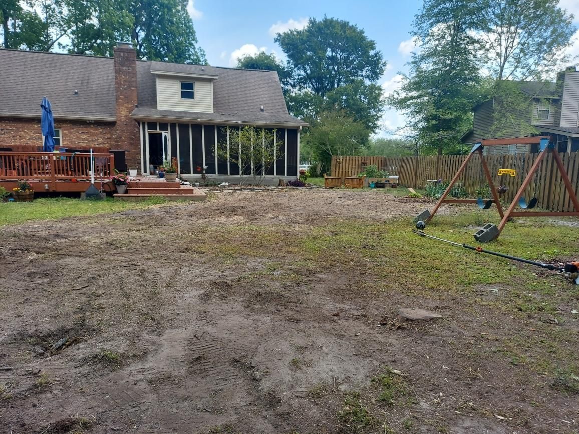 A dirt yard with a house in the background and a swing set in the foreground.