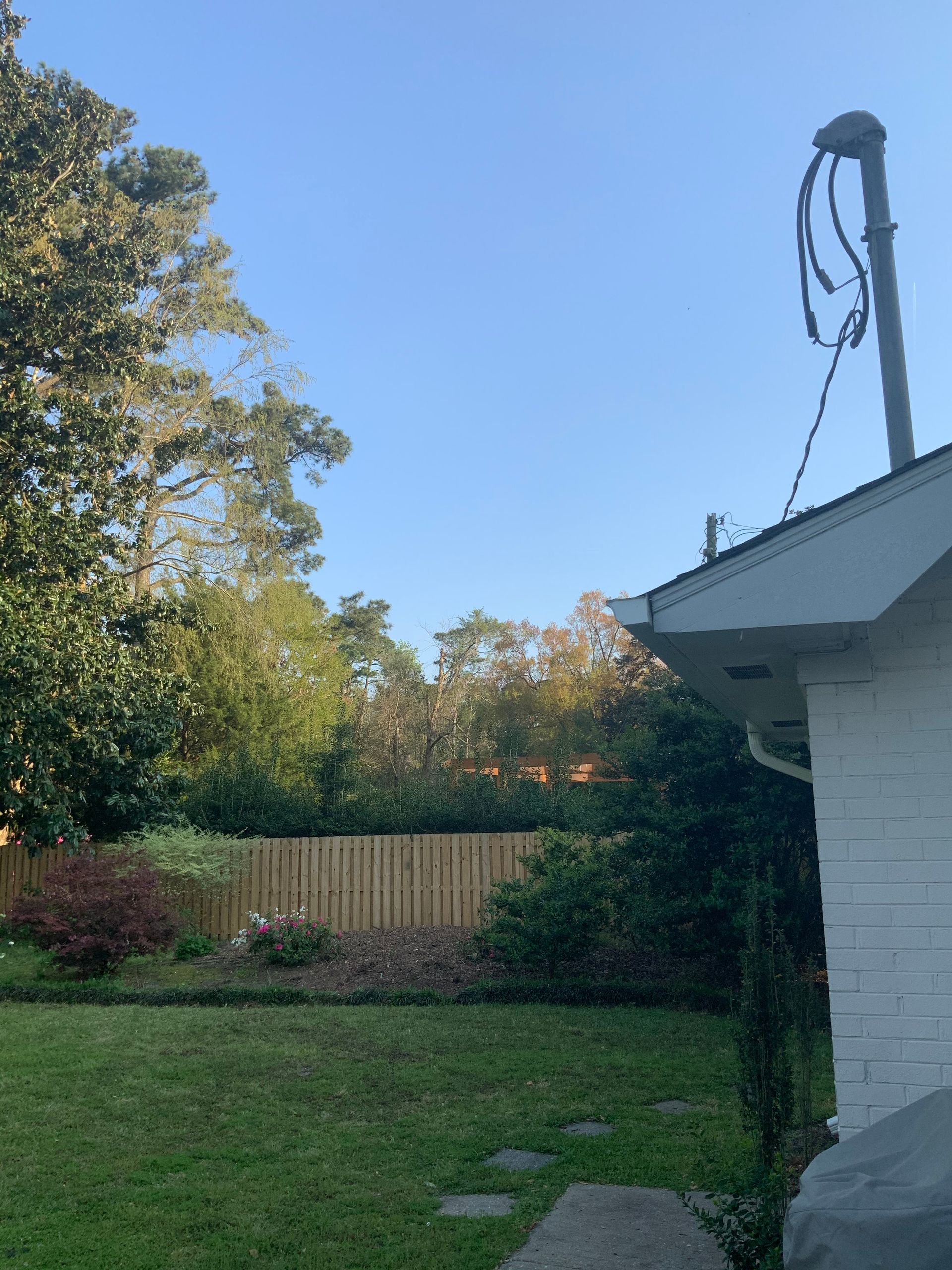 A backyard with a white house and a wooden fence