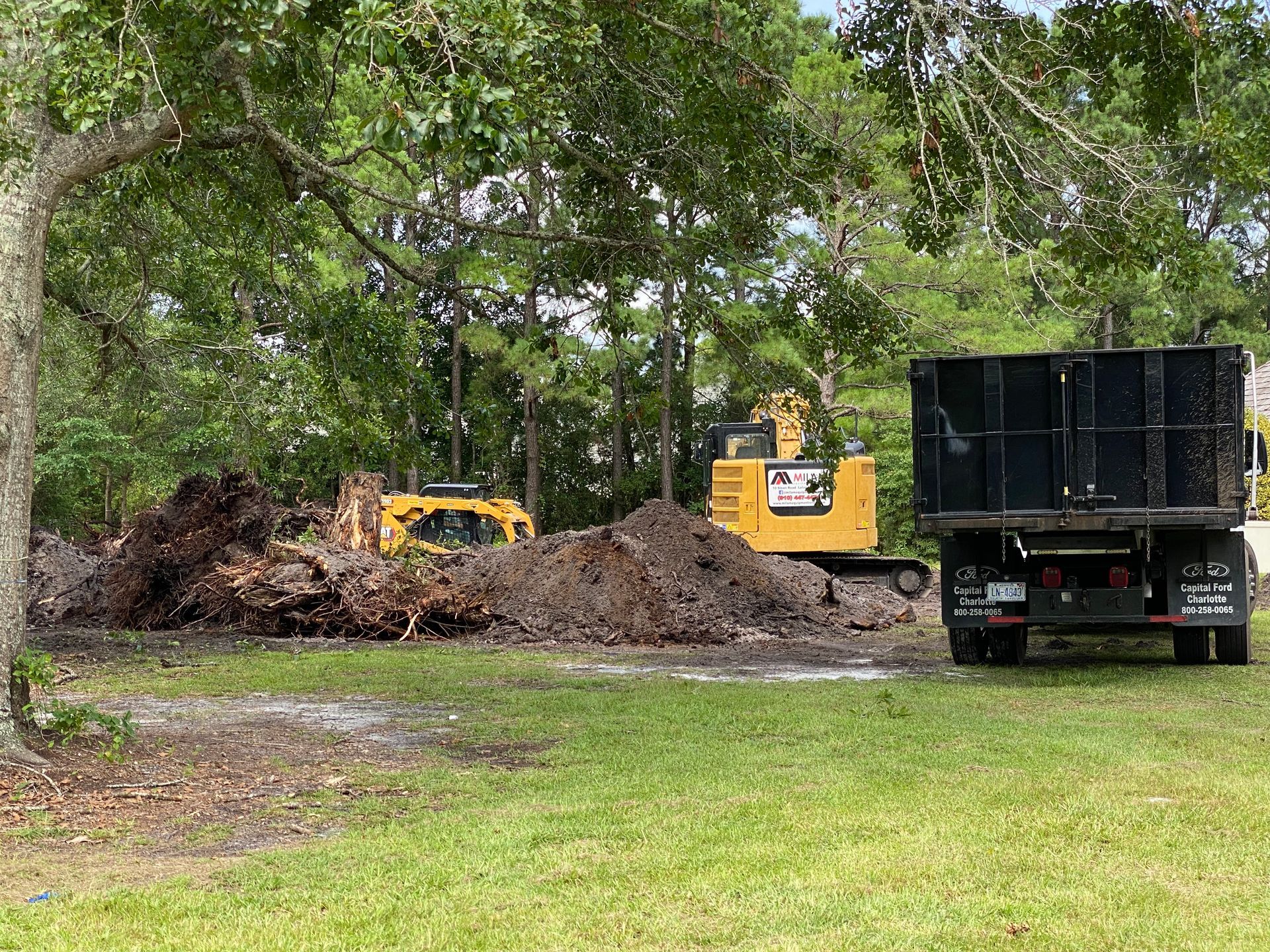 A dump truck is parked in front of a large pile of dirt.