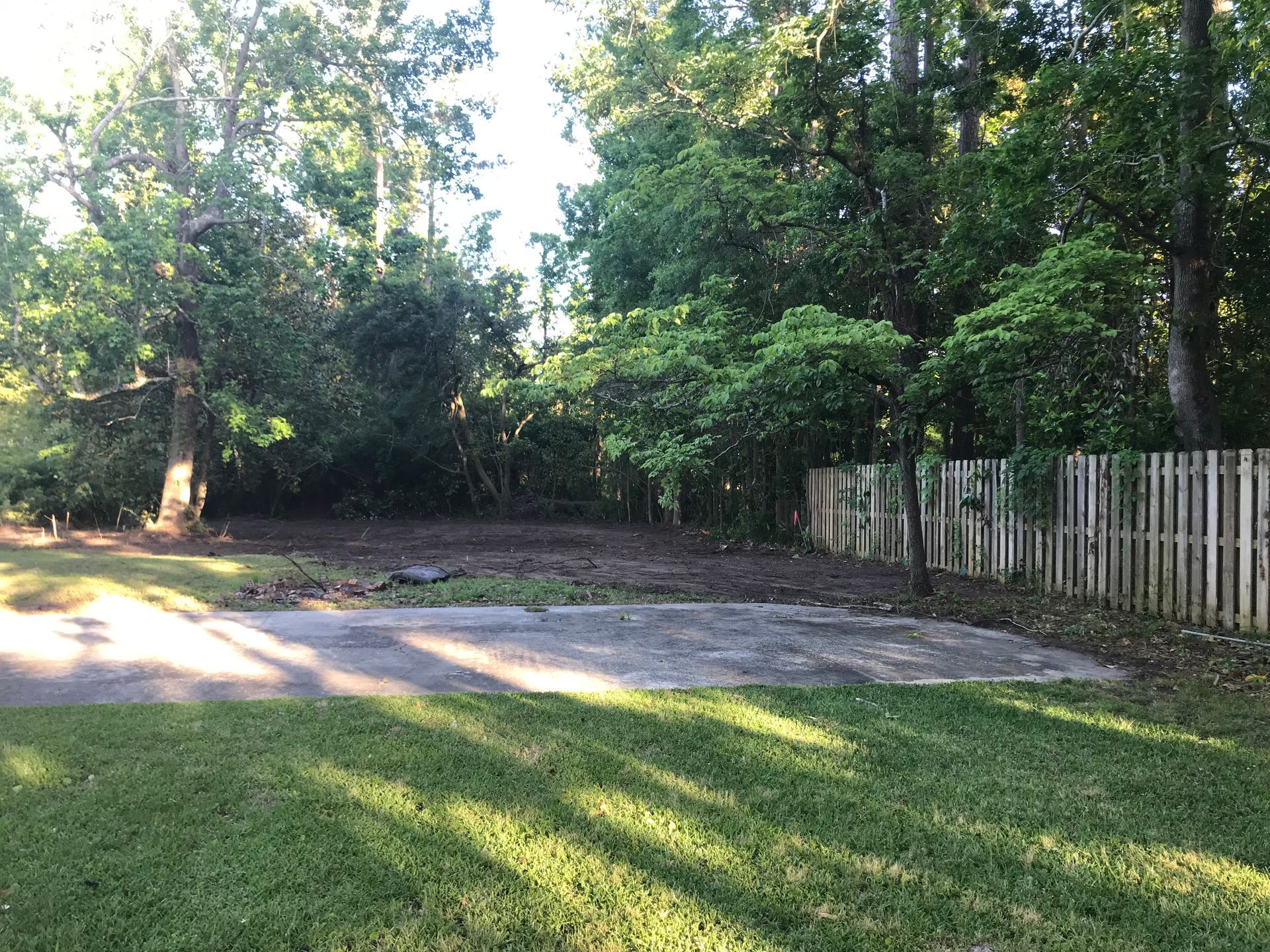A fence surrounds a grassy area with trees in the background.
