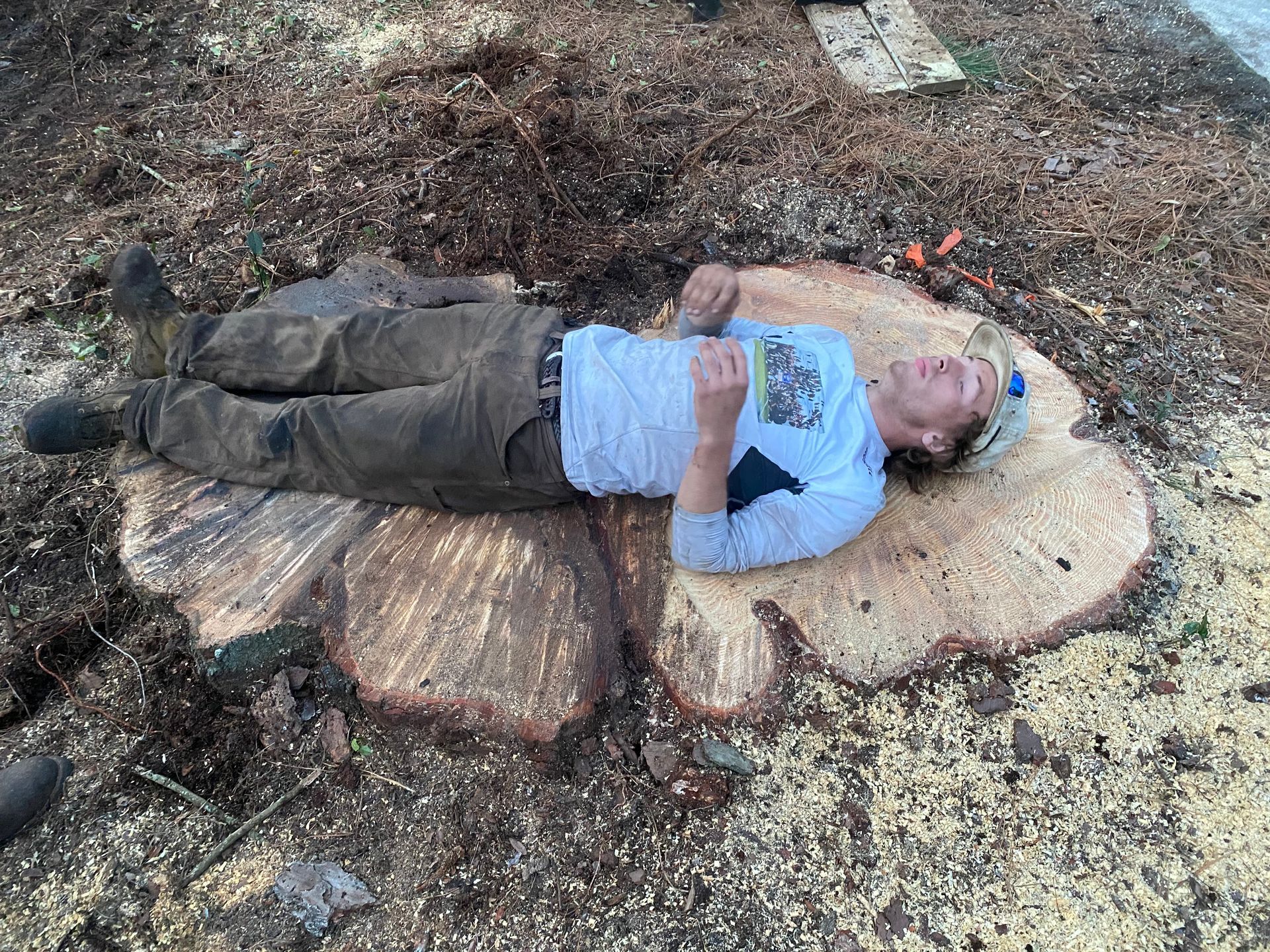 A man is laying on top of a tree stump.