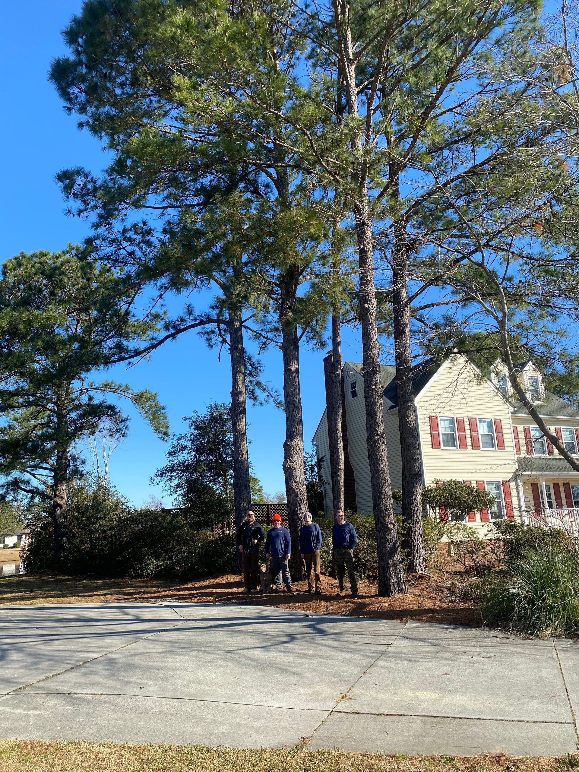 A group of people standing in front of a house surrounded by trees