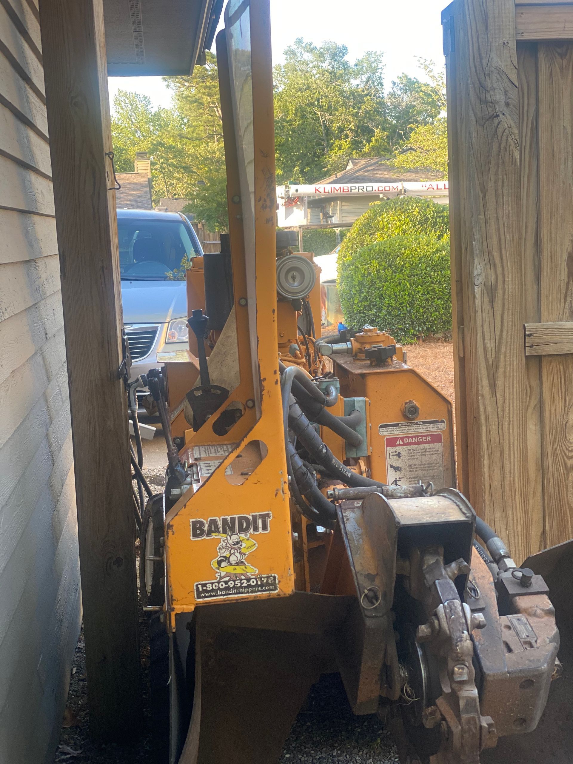 A yellow bandit tractor is parked in front of a house.