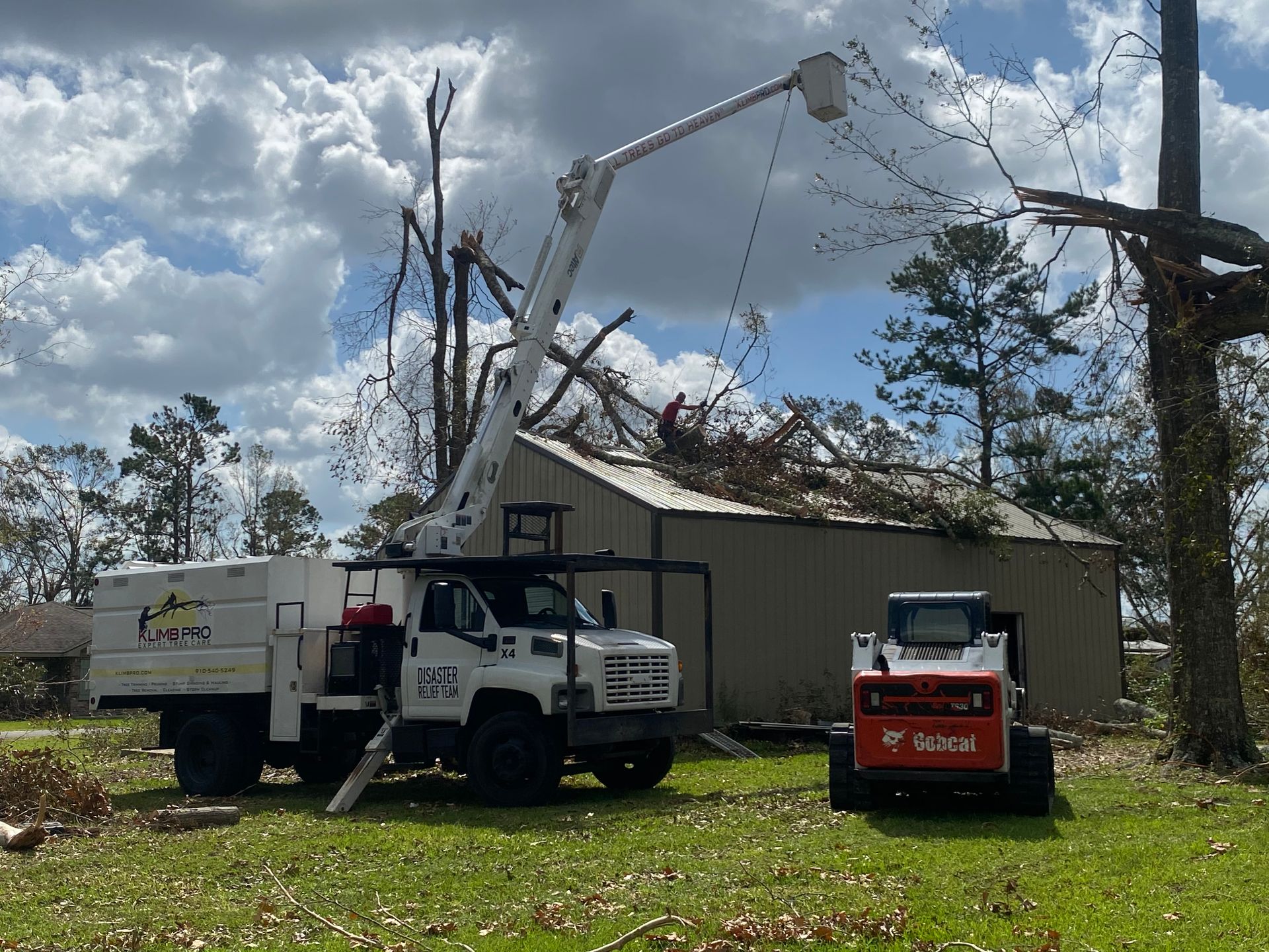 A bobcat truck is parked in front of a house that has been damaged by a storm.