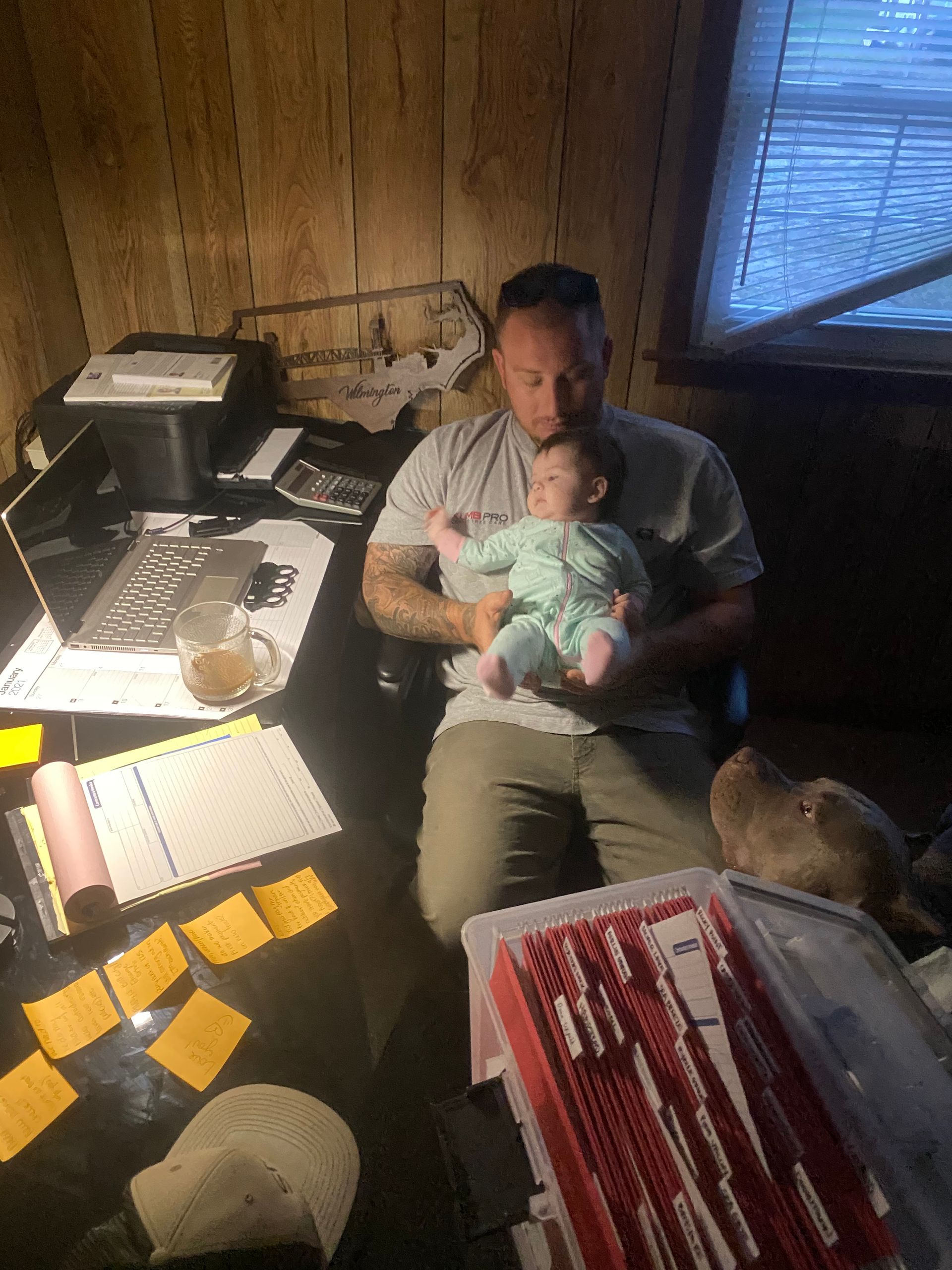 A man is sitting at a desk holding a baby.