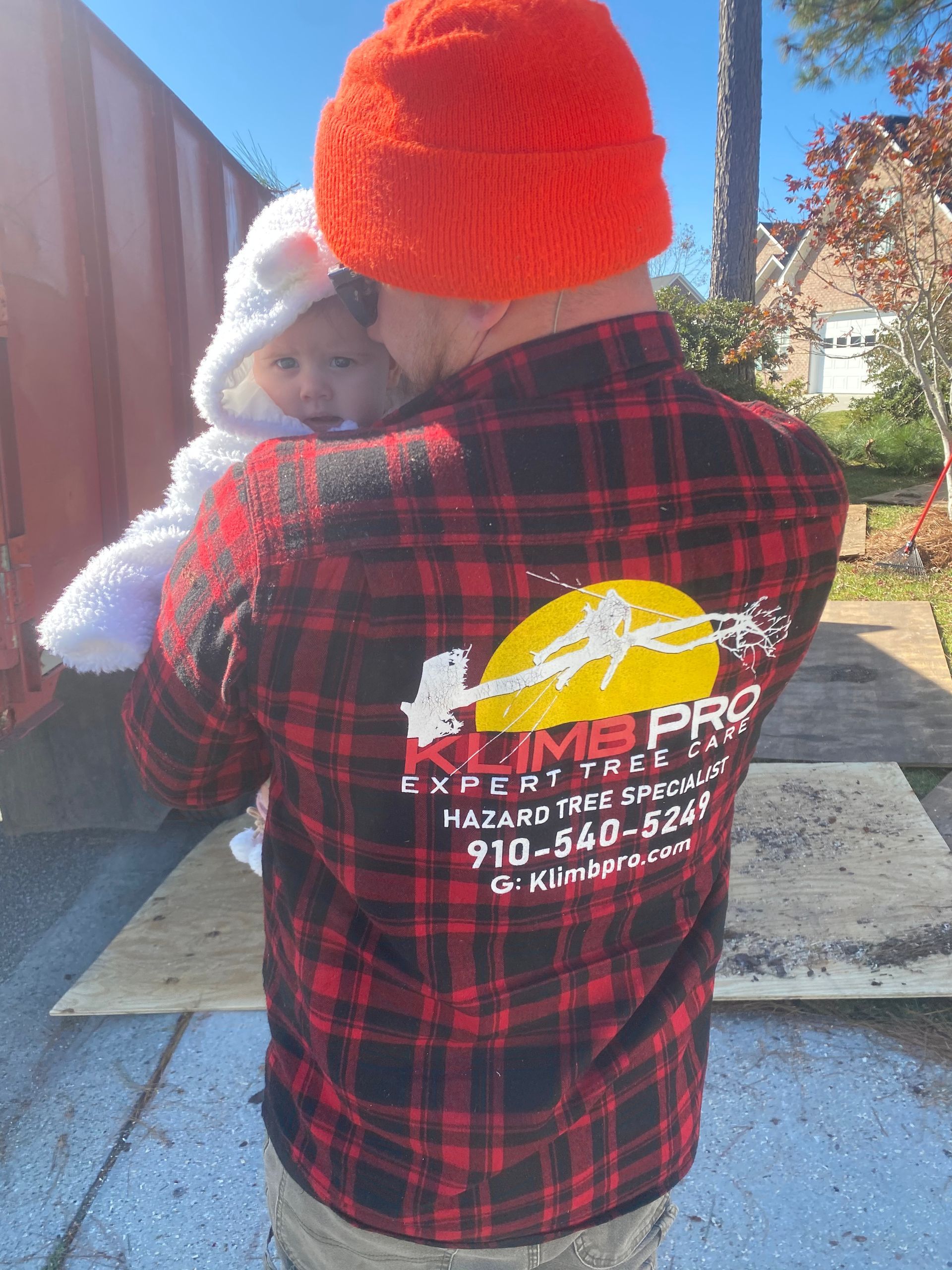 A man in a plaid shirt is holding a baby in his arms.