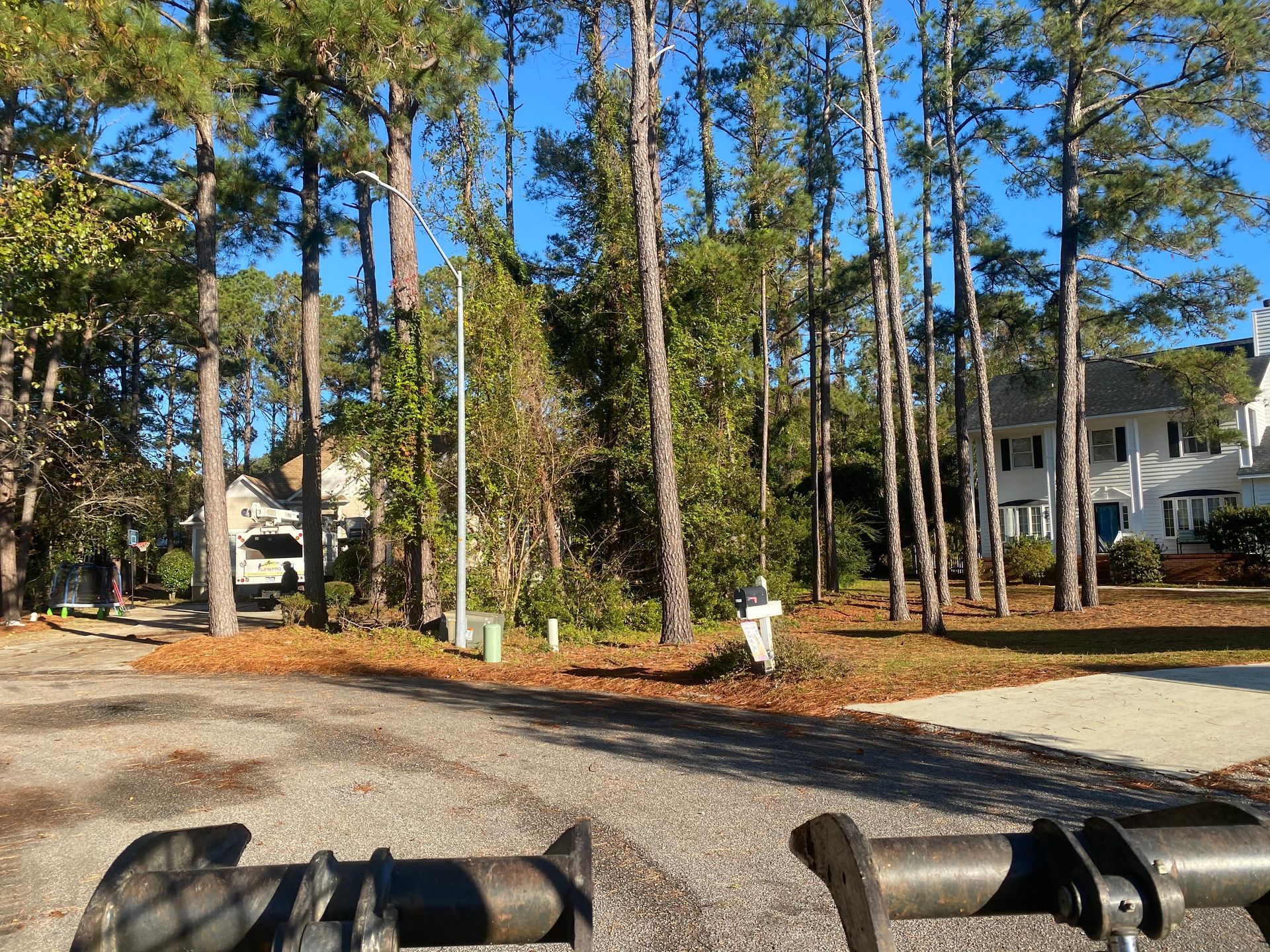 A person is riding a bike down a gravel road with trees in the background.