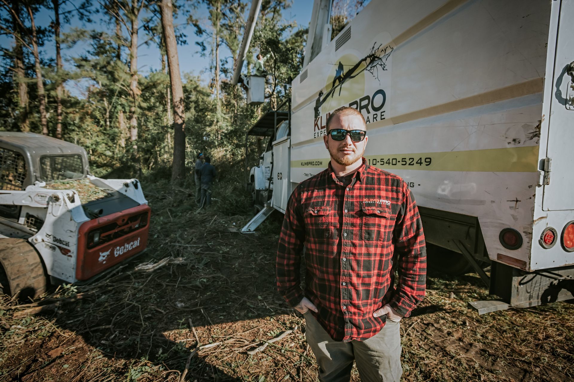 A man in a plaid shirt is standing in front of a truck.