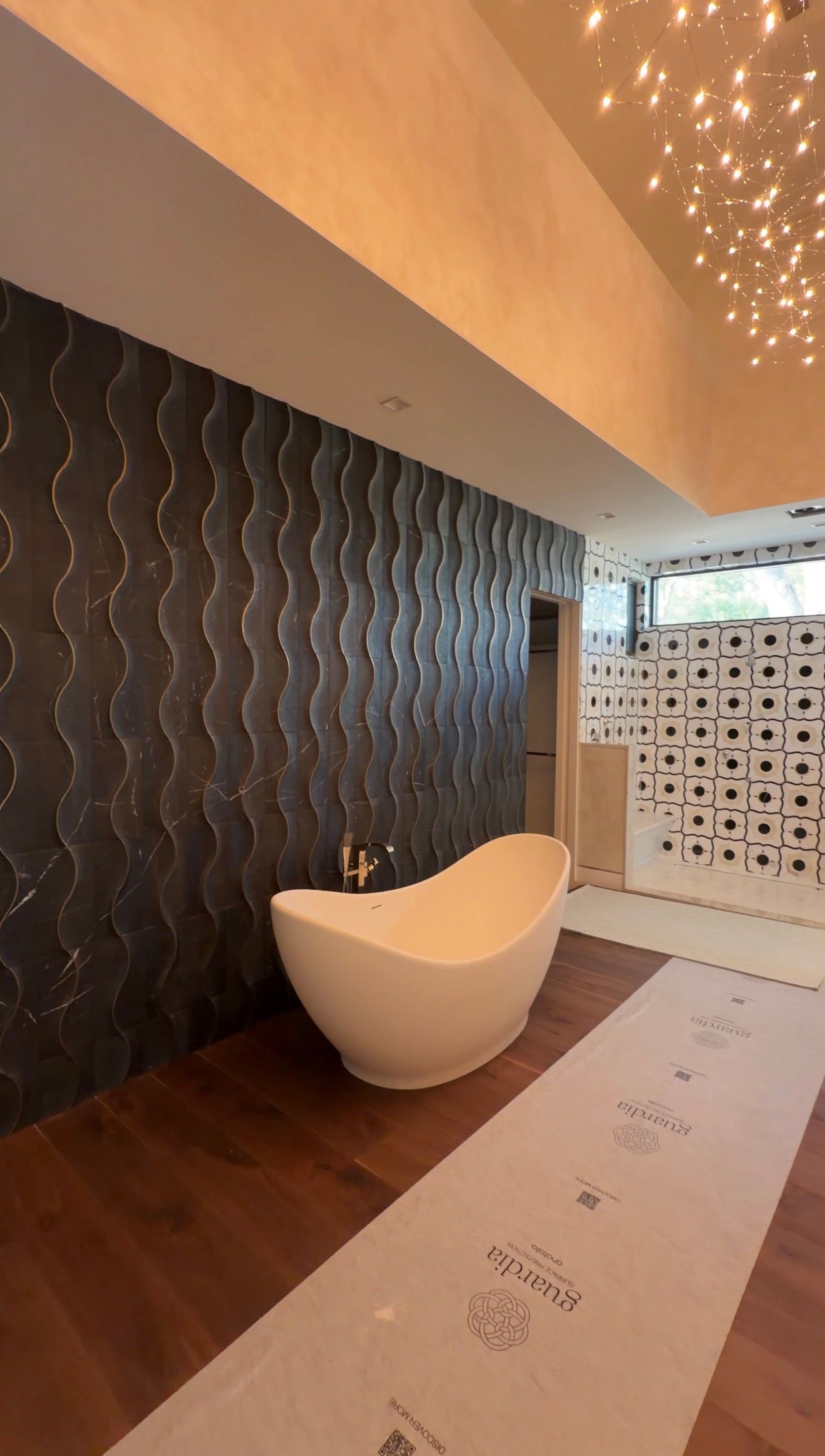 Modern spa interior with a sculptural white chair, dark textured wall, patterned screen, and warm lighting.