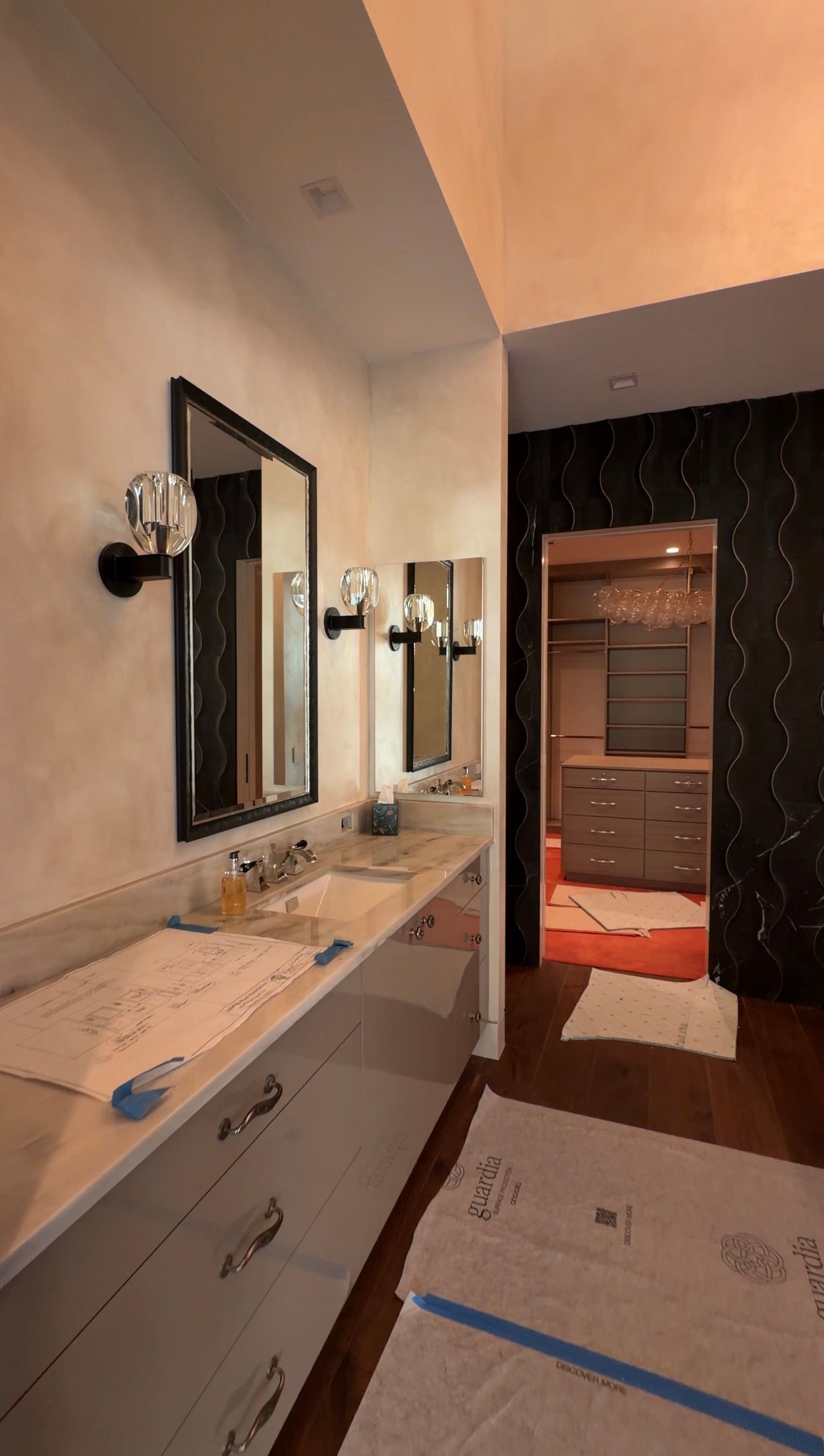 Bathroom vanity with mirror, two wall sconces, and a doorway to a tiled hallway.