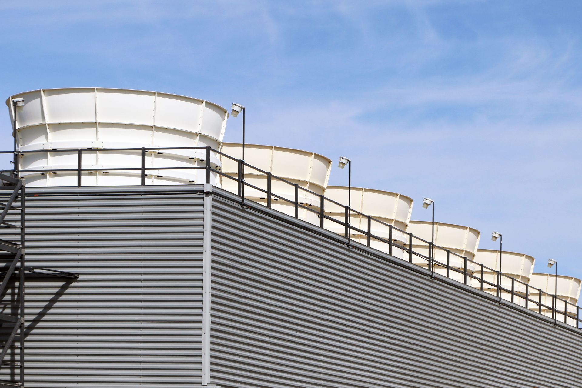 Cooling towers on a building rooftop against a blue sky.