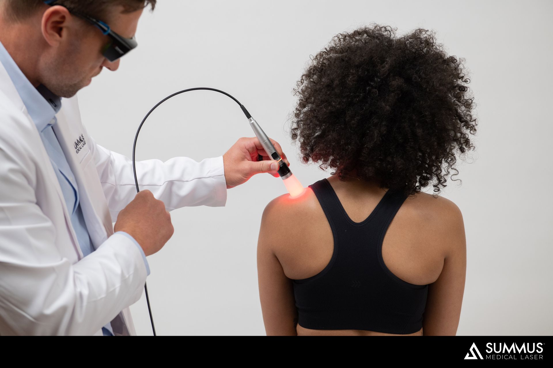 A woman is getting a medical laser therapy treatment on his shoulder.