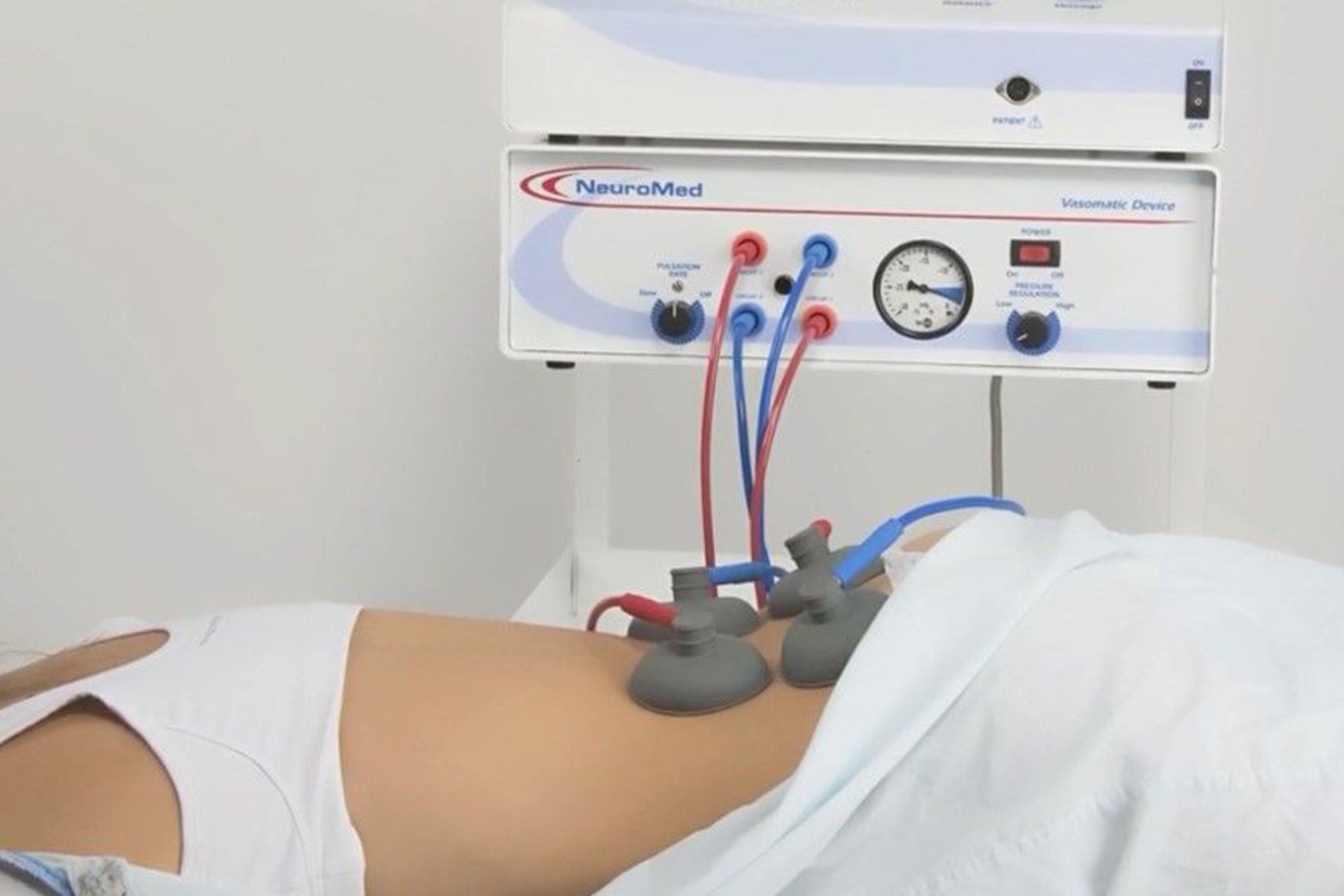 A woman is laying on her stomach in front of a machine that has a clock on it