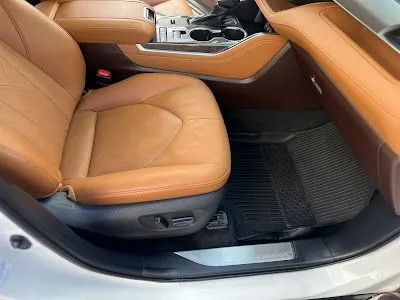 Tan leather car interior with black floor mat.