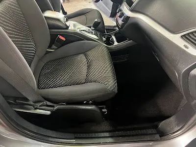 Grey car interior with black seats and carpet. Focus on the front driver's side.
