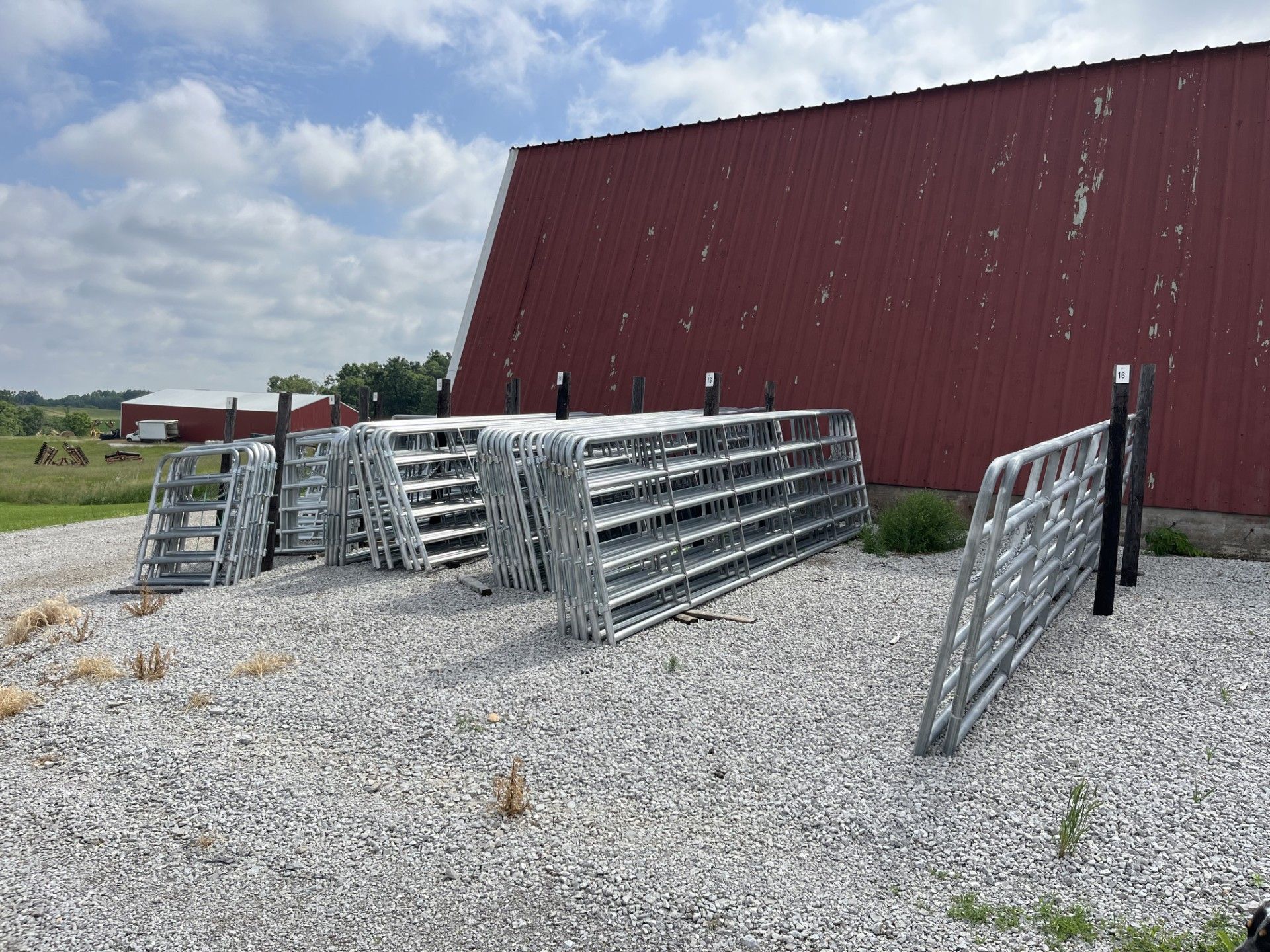 A bunch of metal fences are stacked on top of each other in front of a red barn.