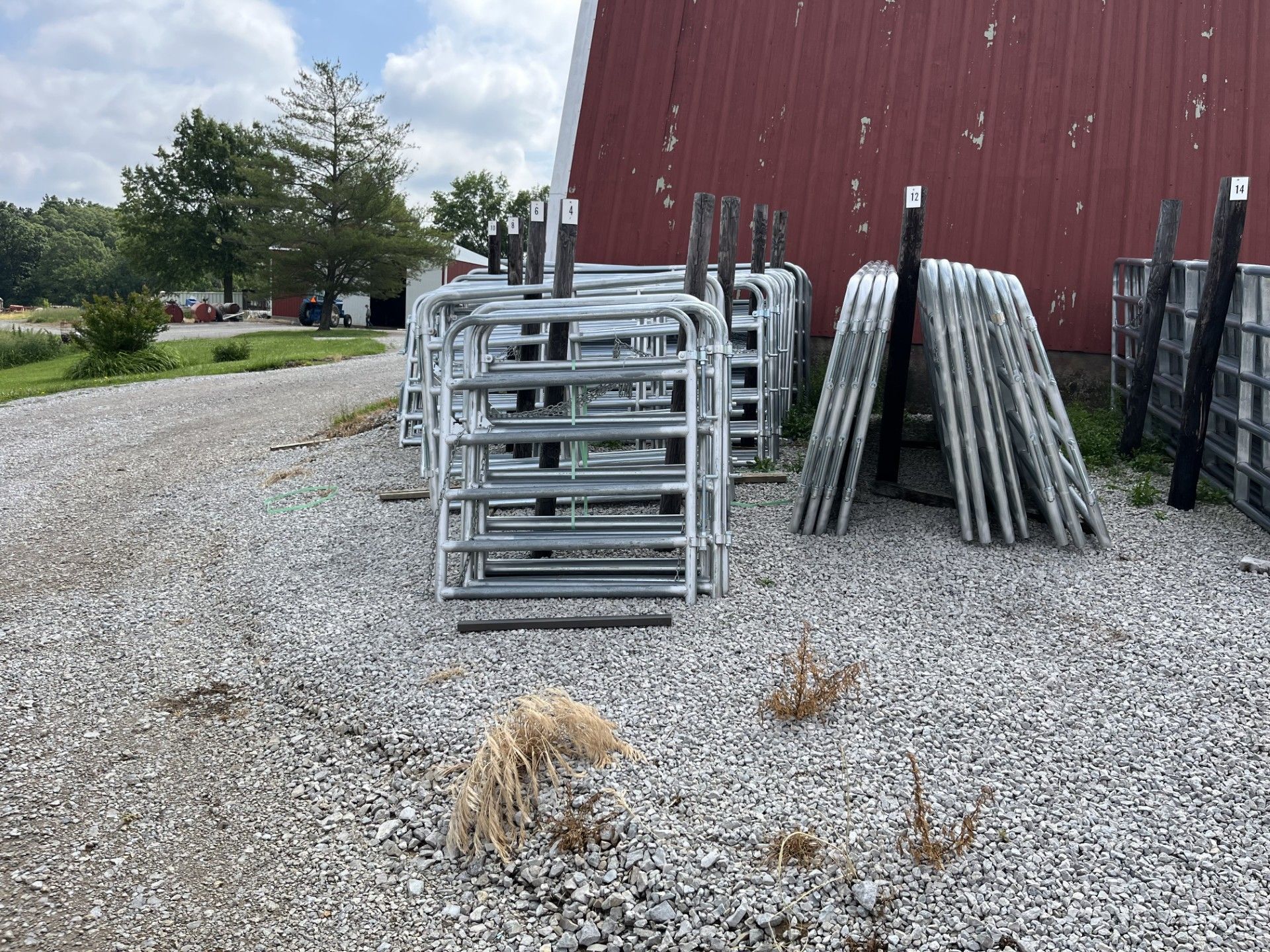 A bunch of metal fences are stacked on top of each other in a gravel area.