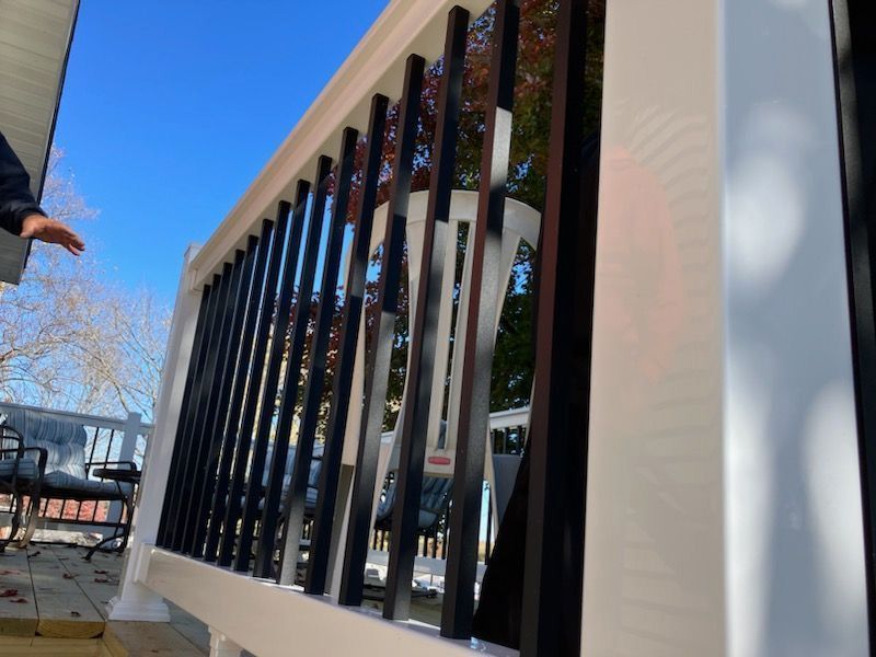 A wooden deck with newly installed white and black railing