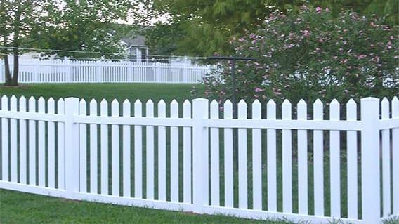 A white picket fence surrounds a lush green yard.