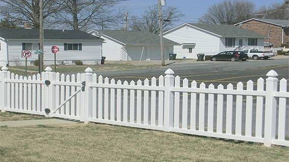 A white picket fence with a gate in front of a house.