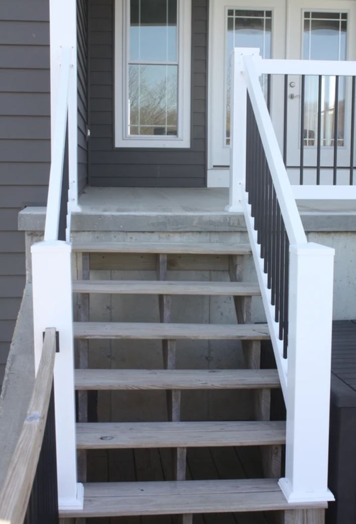 A set of stairs leading up to a porch with a white railing