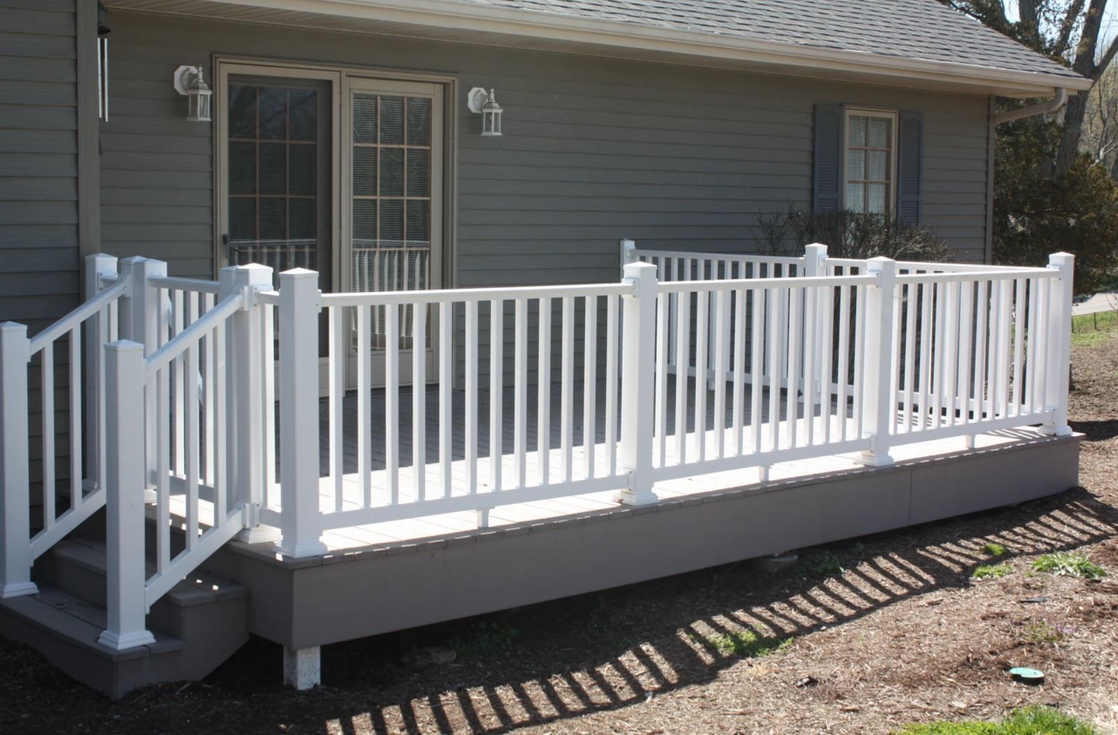 A gray house with a white railing on the deck