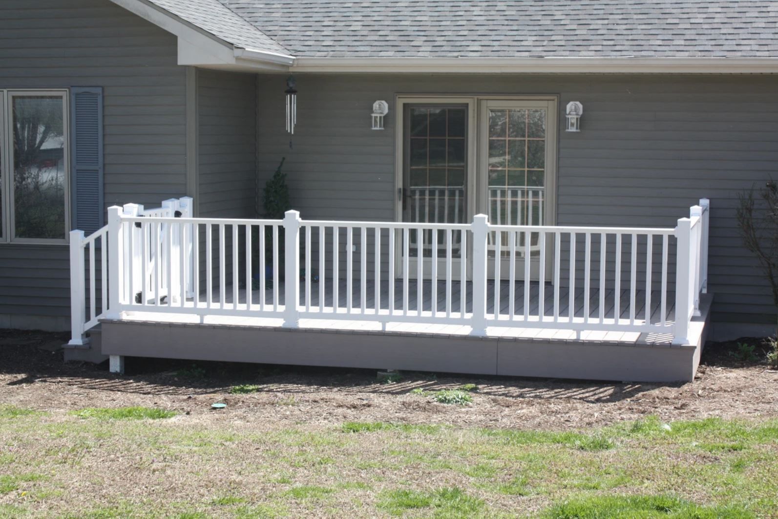 A gray house with a white deck in front of it