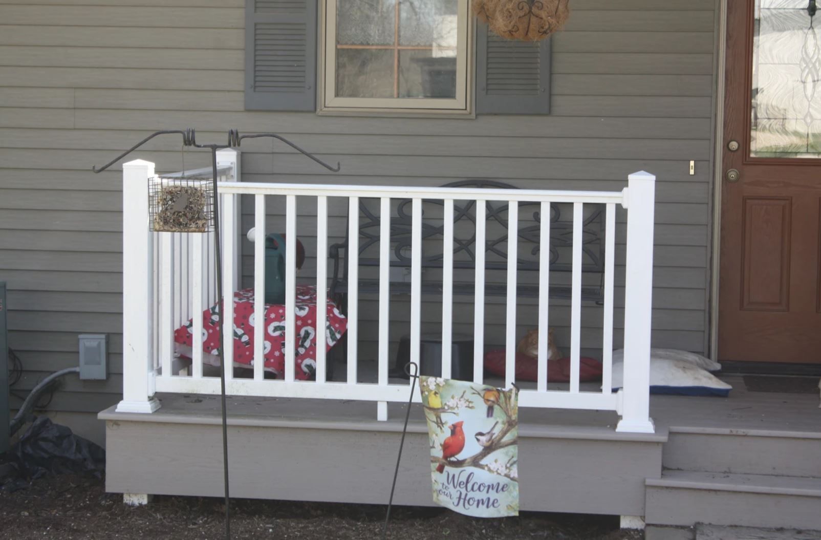 A porch with a white railing and a bird feeder on it