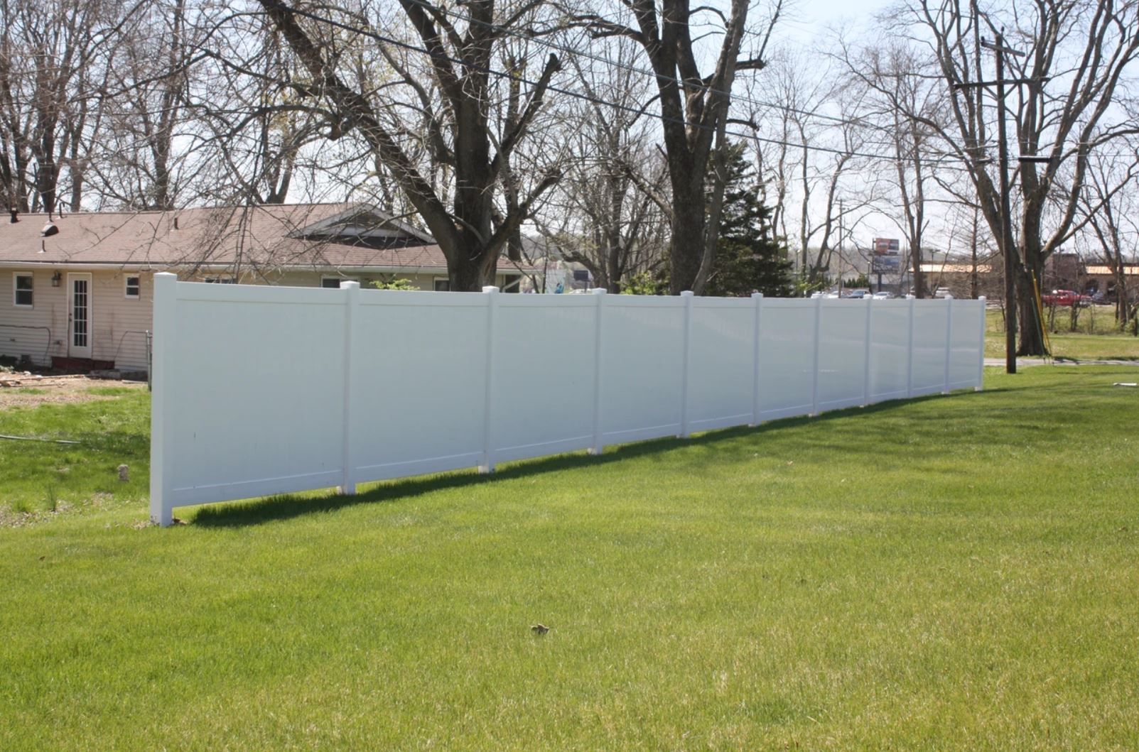 A white fence is sitting in the middle of a lush green field.