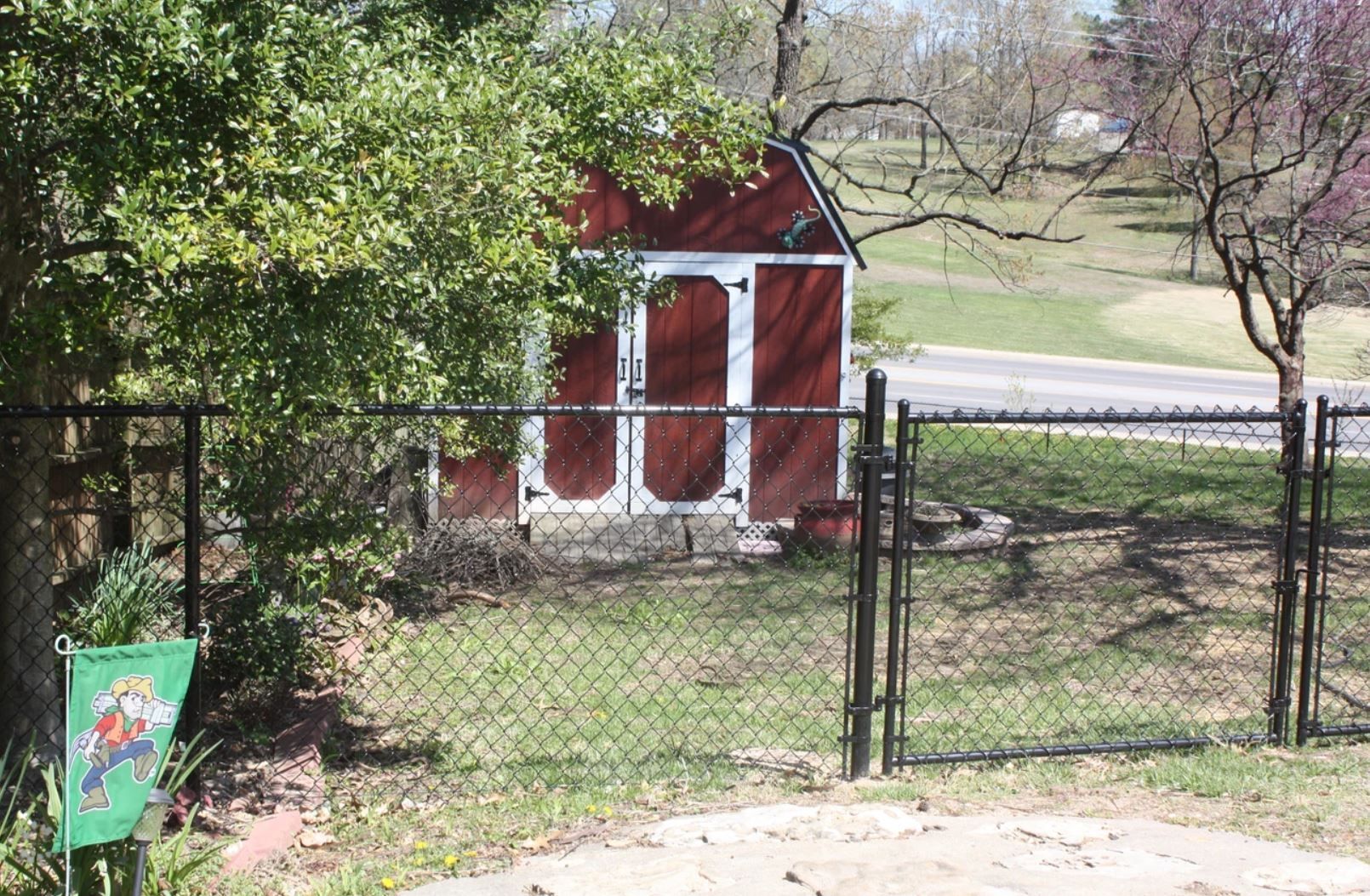 A red barn is behind a chain link fence